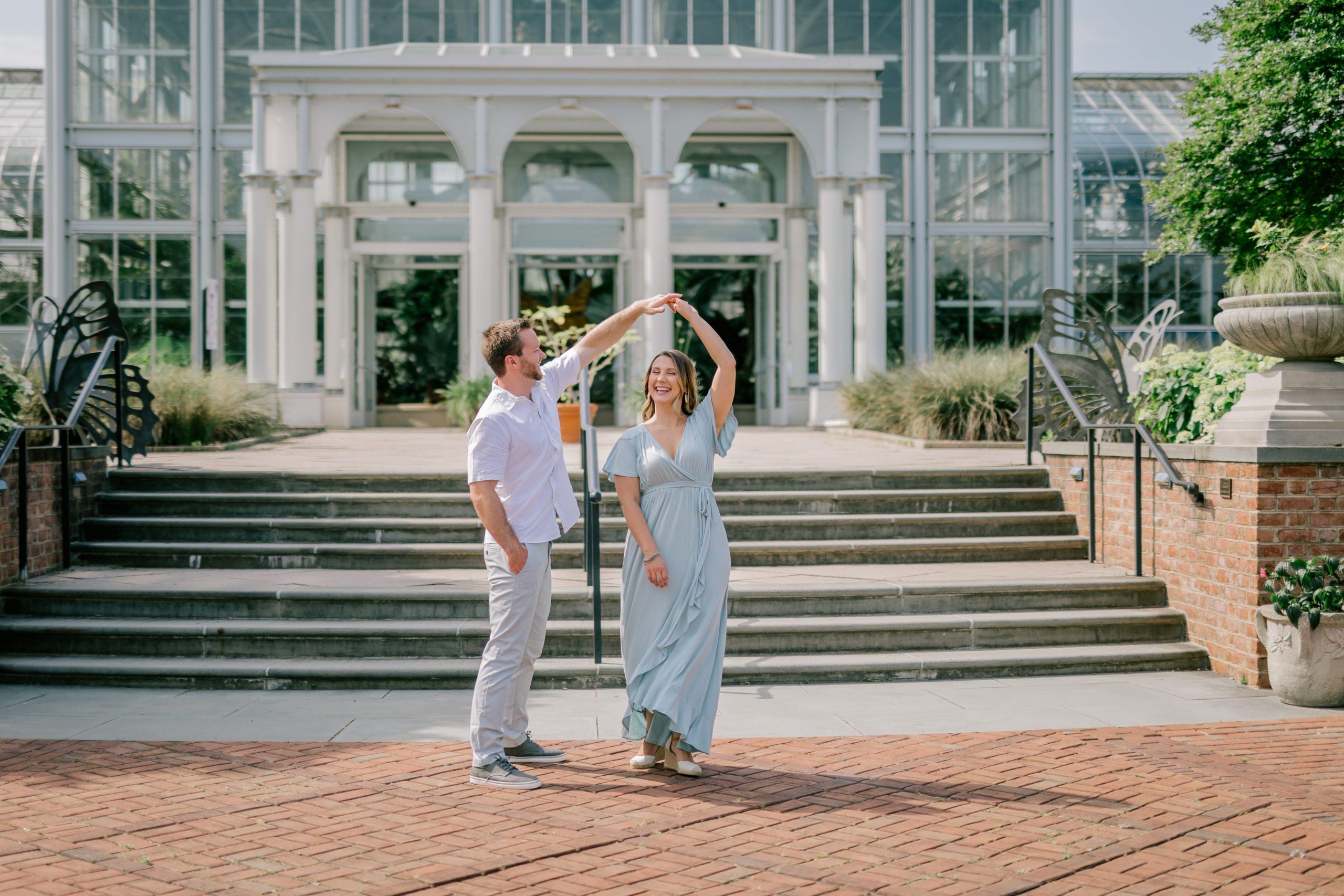 Couple dancing in front of conservatory - Lewis Ginter Botanical Garden Engagement Session - Garden Engagement Session