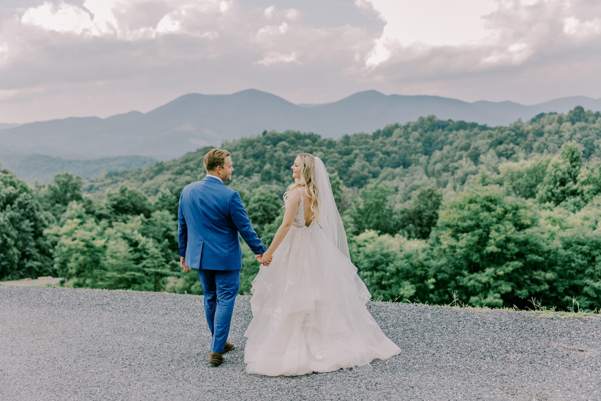 Bride and groom walking away from camera with tons of trees and mountains as the landscape view