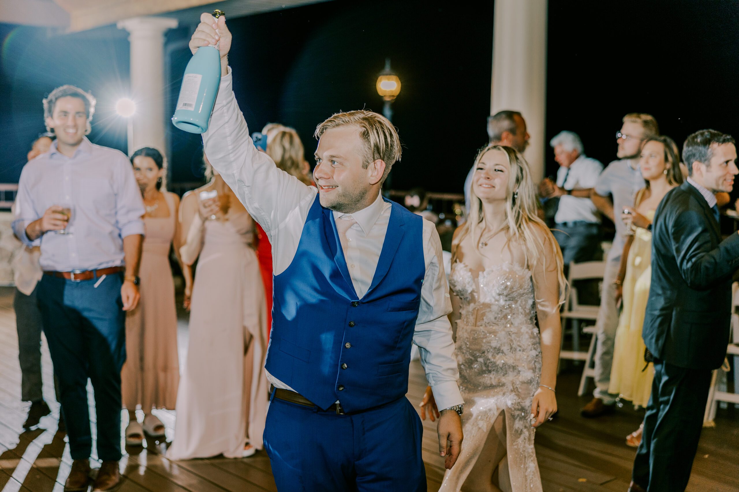 Groom dancing at his reception with bride, and other guests in background