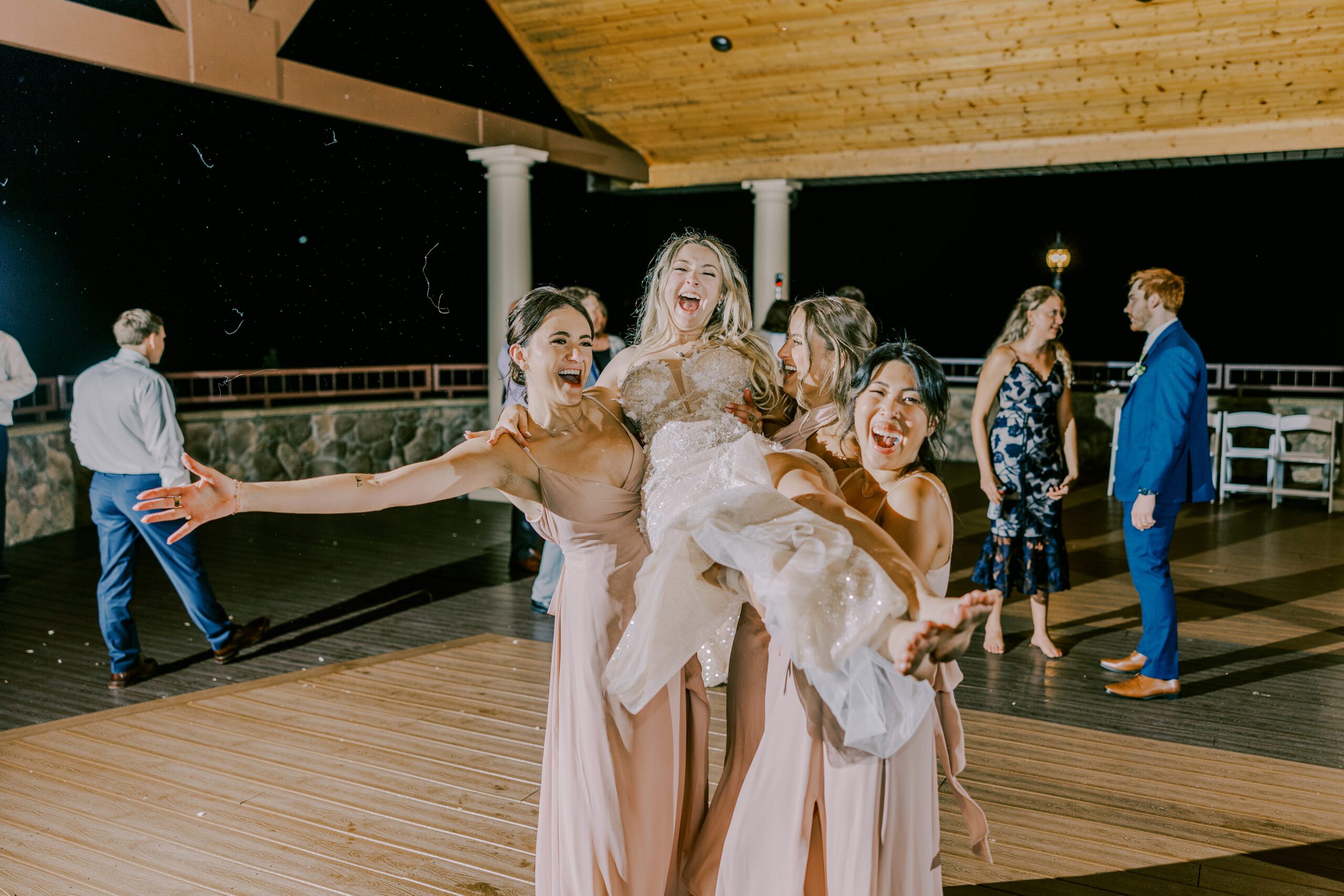 Three bridesmaids carrying bride on the dance floor