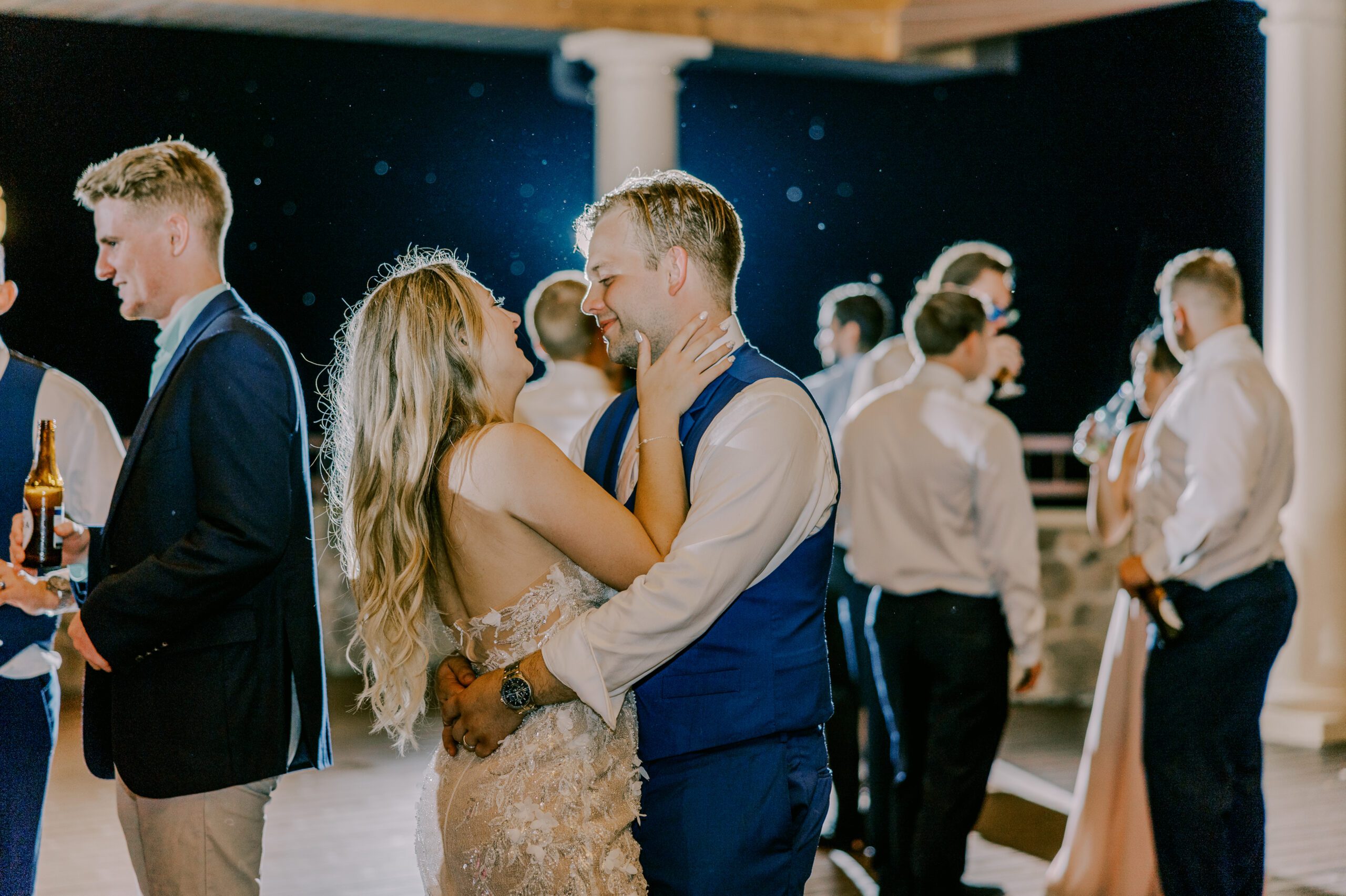 Bride and groom holding each other dancing as other guests dance in background
