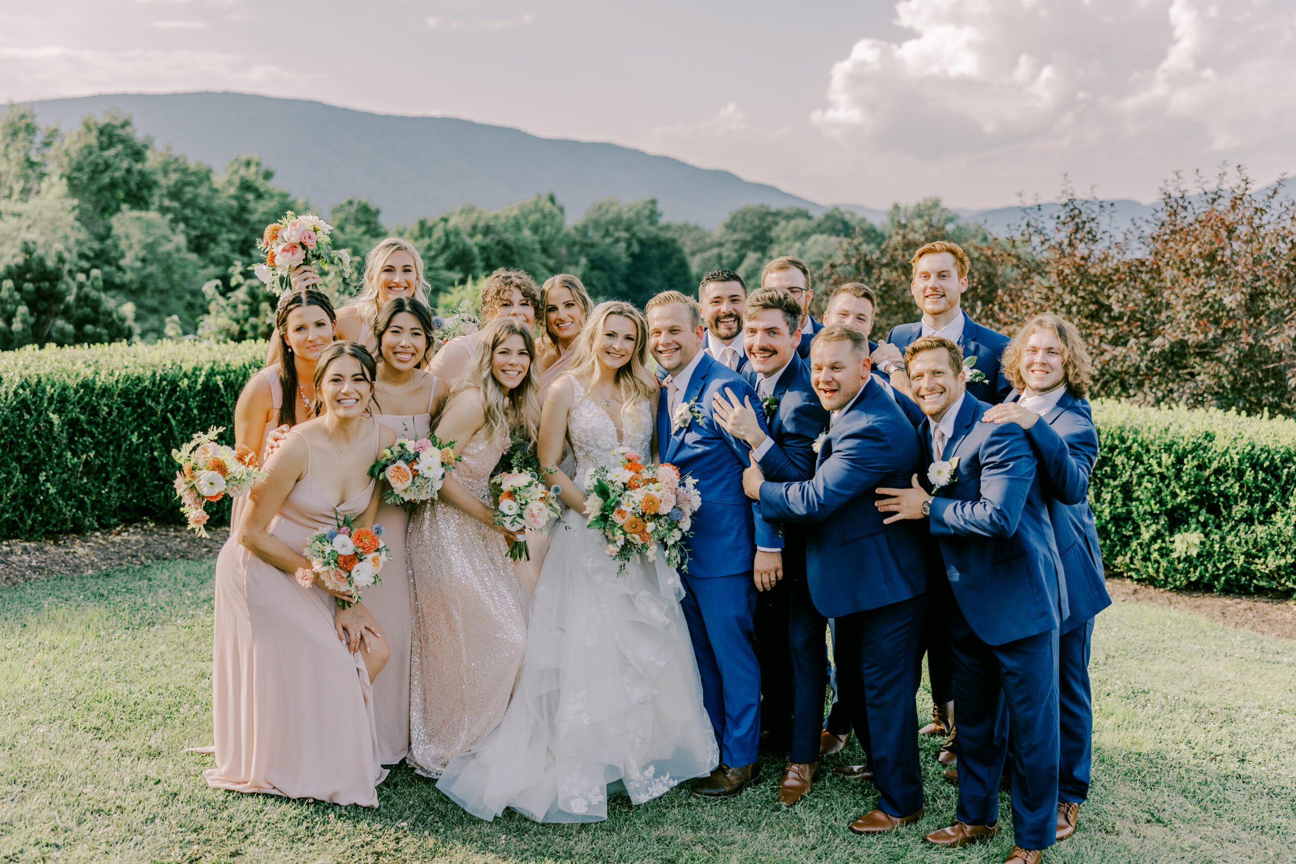 Bride and groom smiling as they're surrounded by bridesmaids and groomsmen huddled in