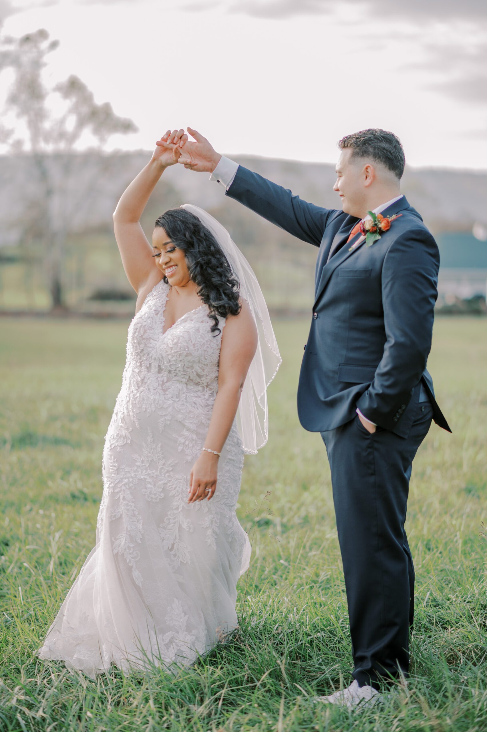 Couple dancing outside in the grass, groom spinning bride around, smiles on both their faces