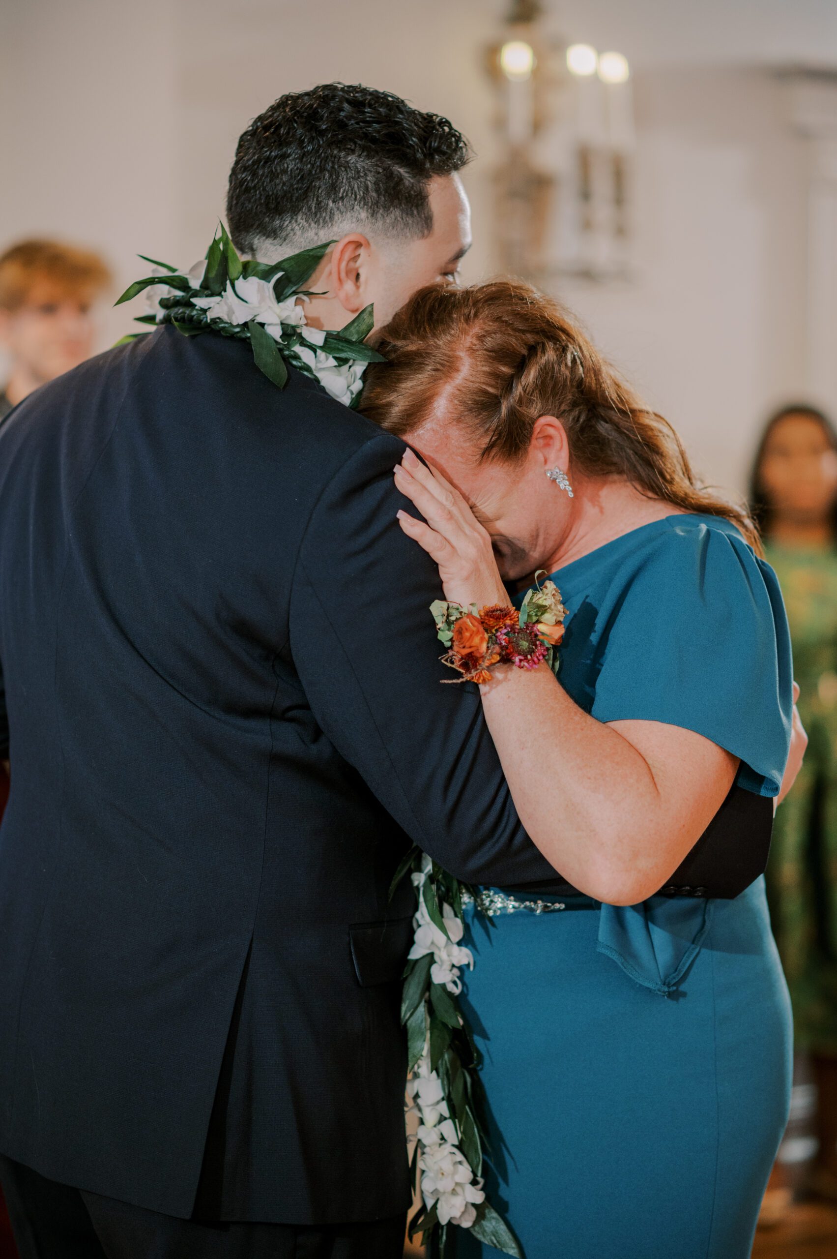Groom and his mother embracing, mother with her face buired into groom's shoulder