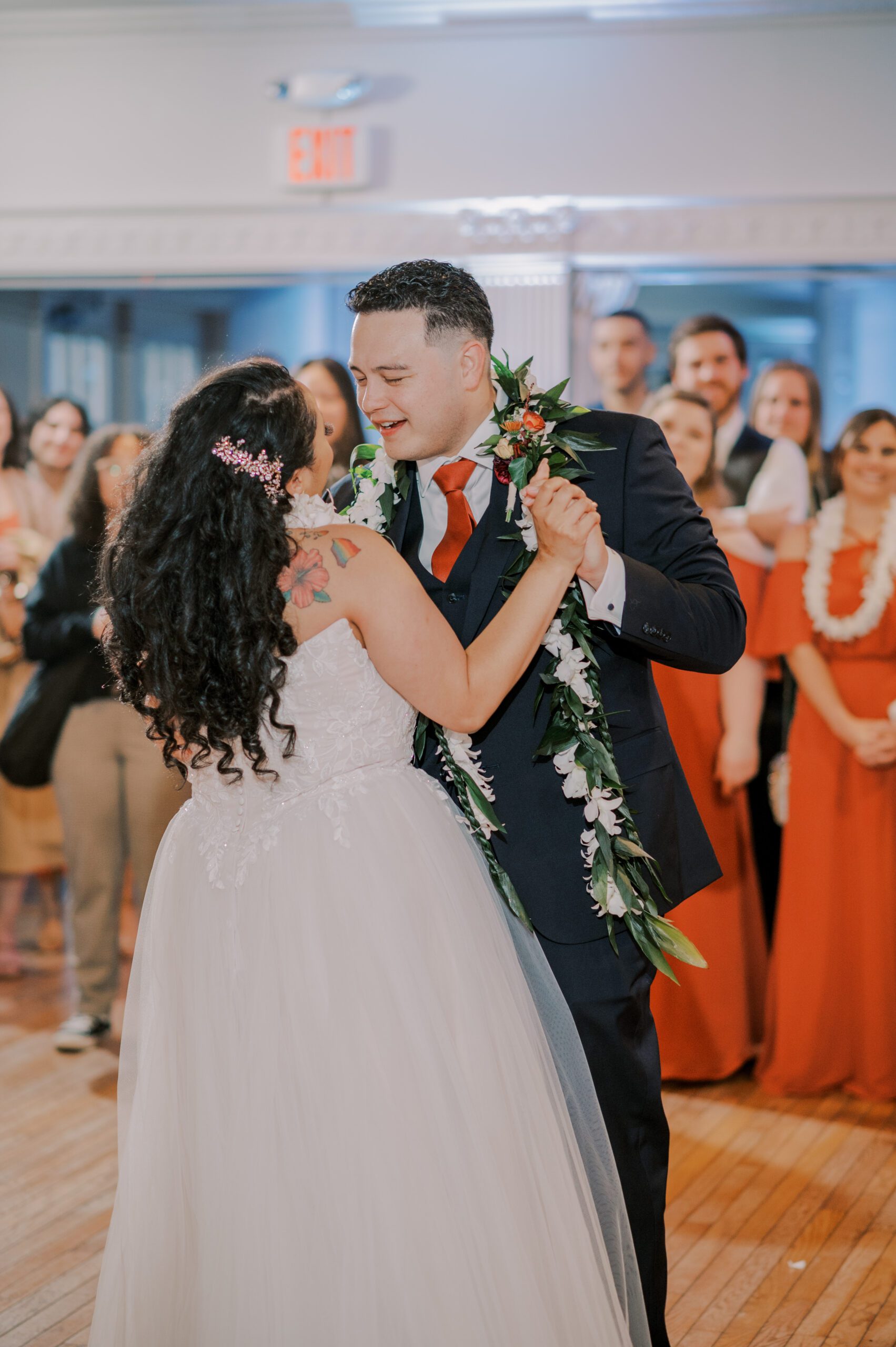 Image of groom dancing with bride, as guests and bridal party watch in background of photo