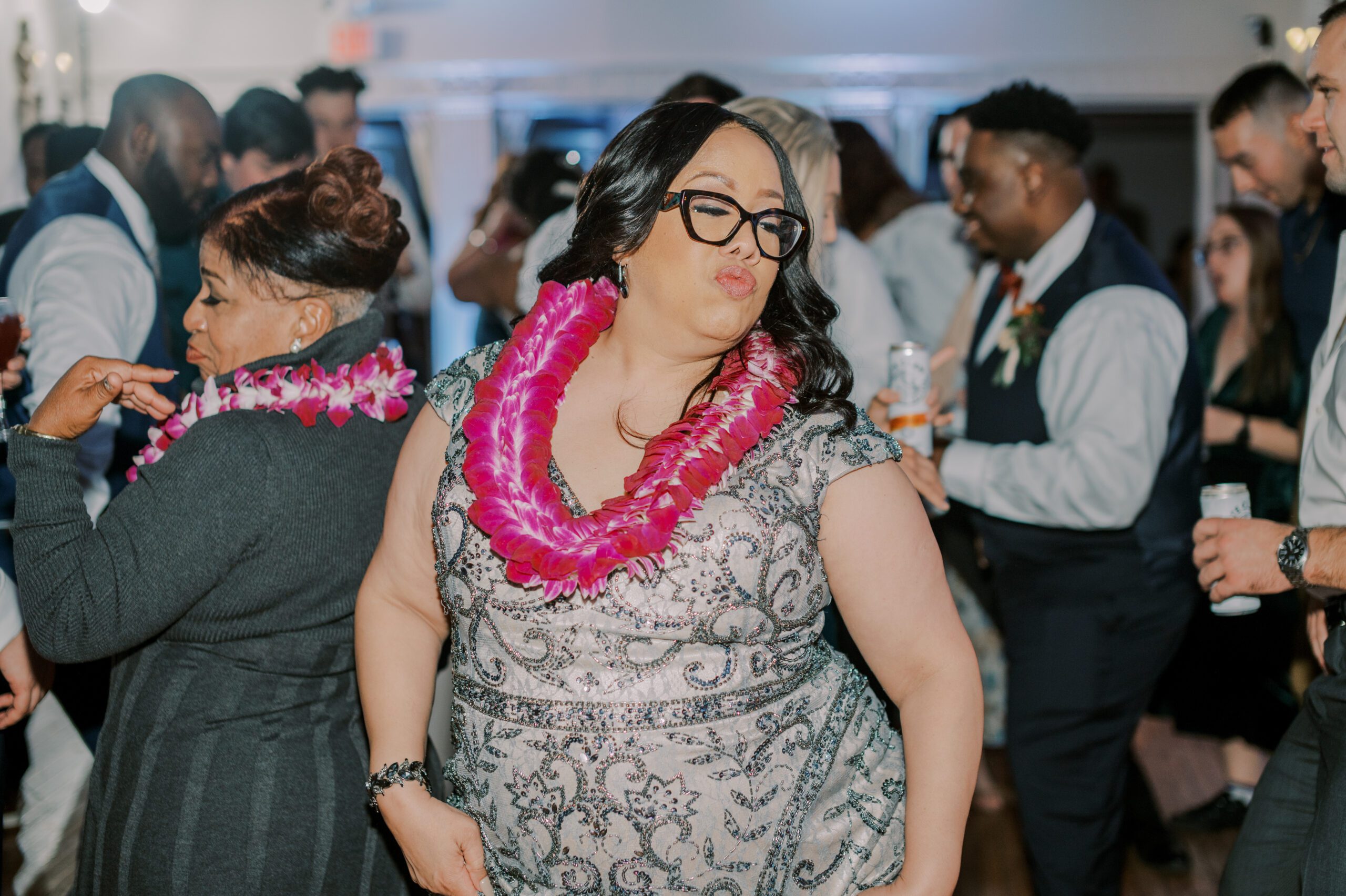 Woman on dance floor in a grey dress wearing a pink lei at the manor at airmont