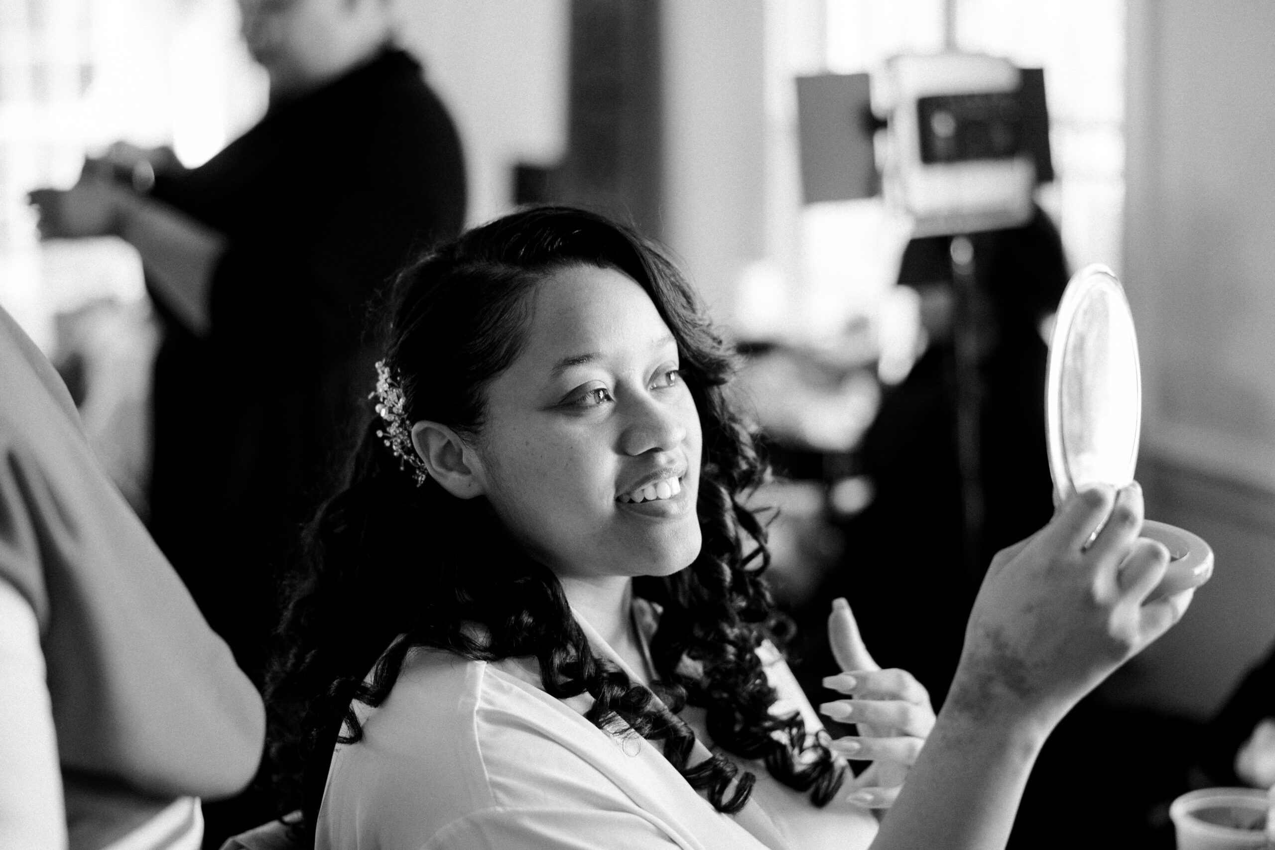 Black and white image of bride admiring her hair freshly styled at the manor at airmont