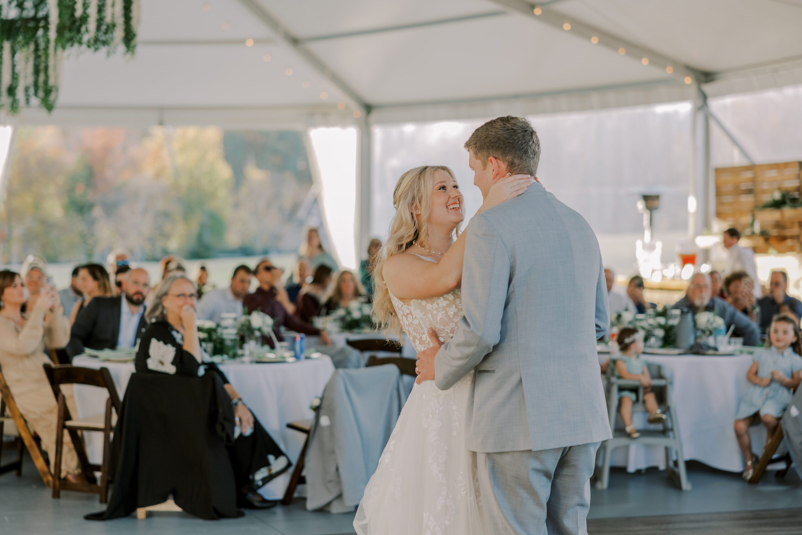 Image of bride and groom dancing at their reception at arbor haven, looking at each other, with guest sitting at tables behind them