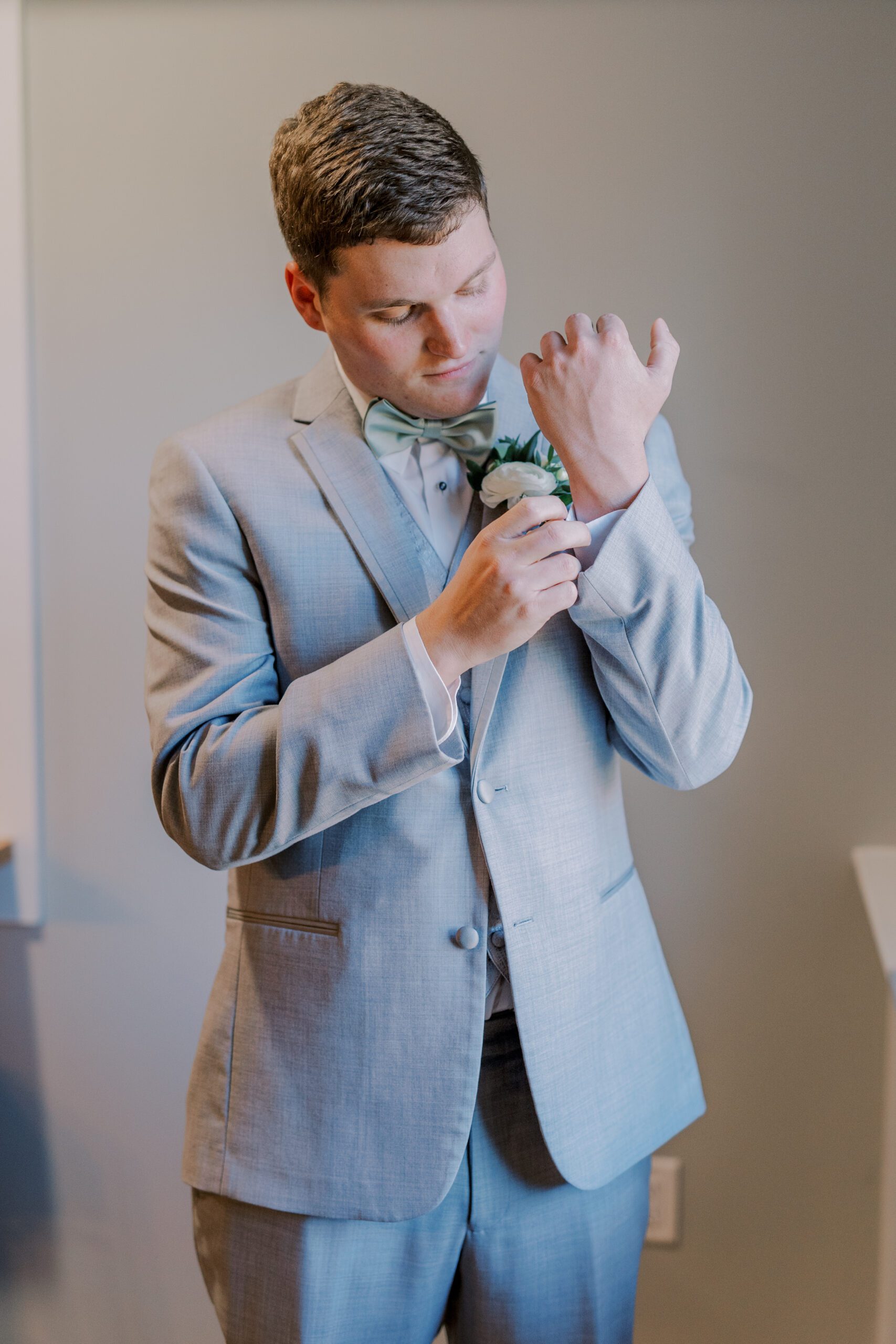 Solo photo of groom in his light grey suit adjusting the cuff of his shirt at arbor haven