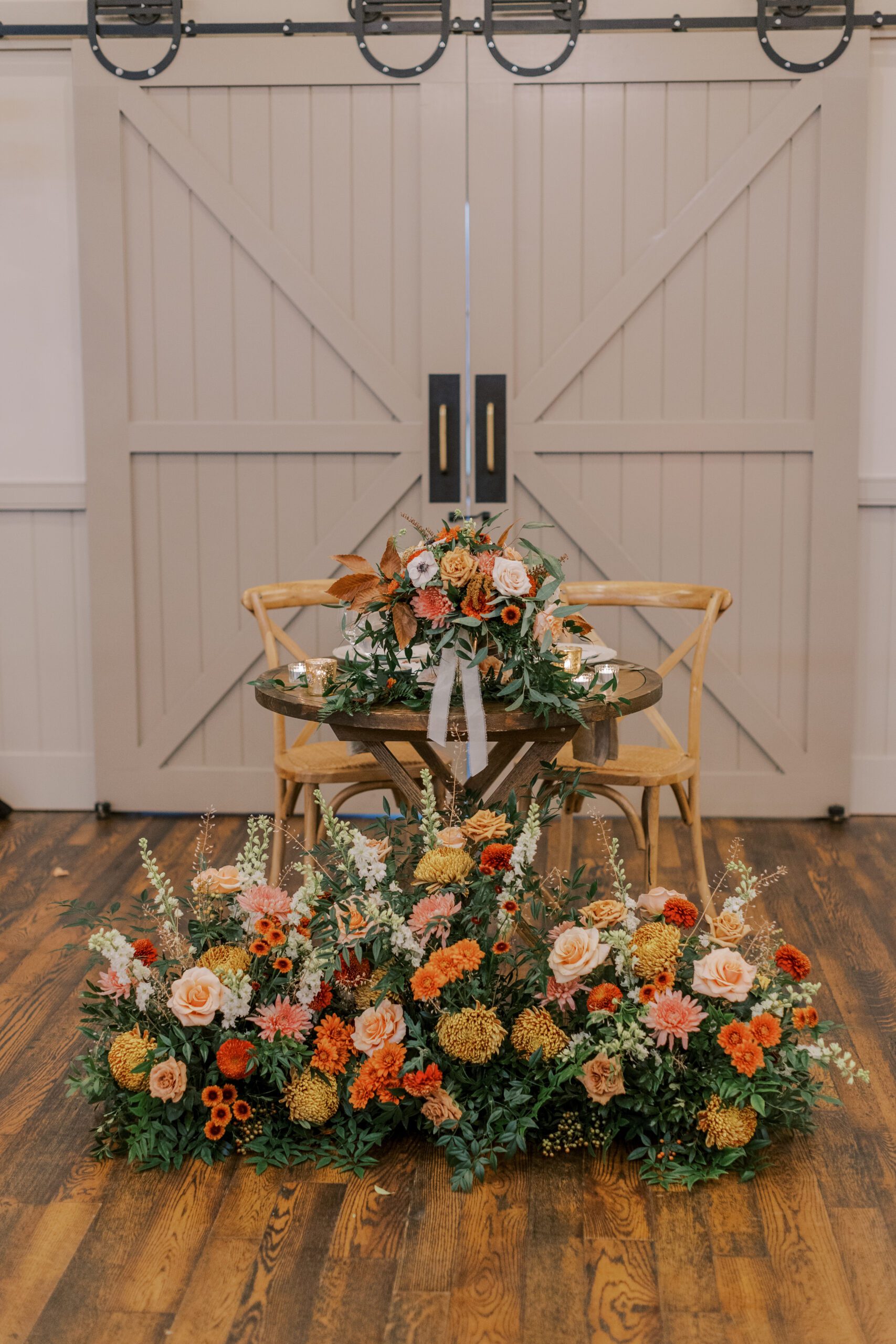 Bride and Groom's table at the reception covered in all kinds of orange, peach, and yellow flowers.