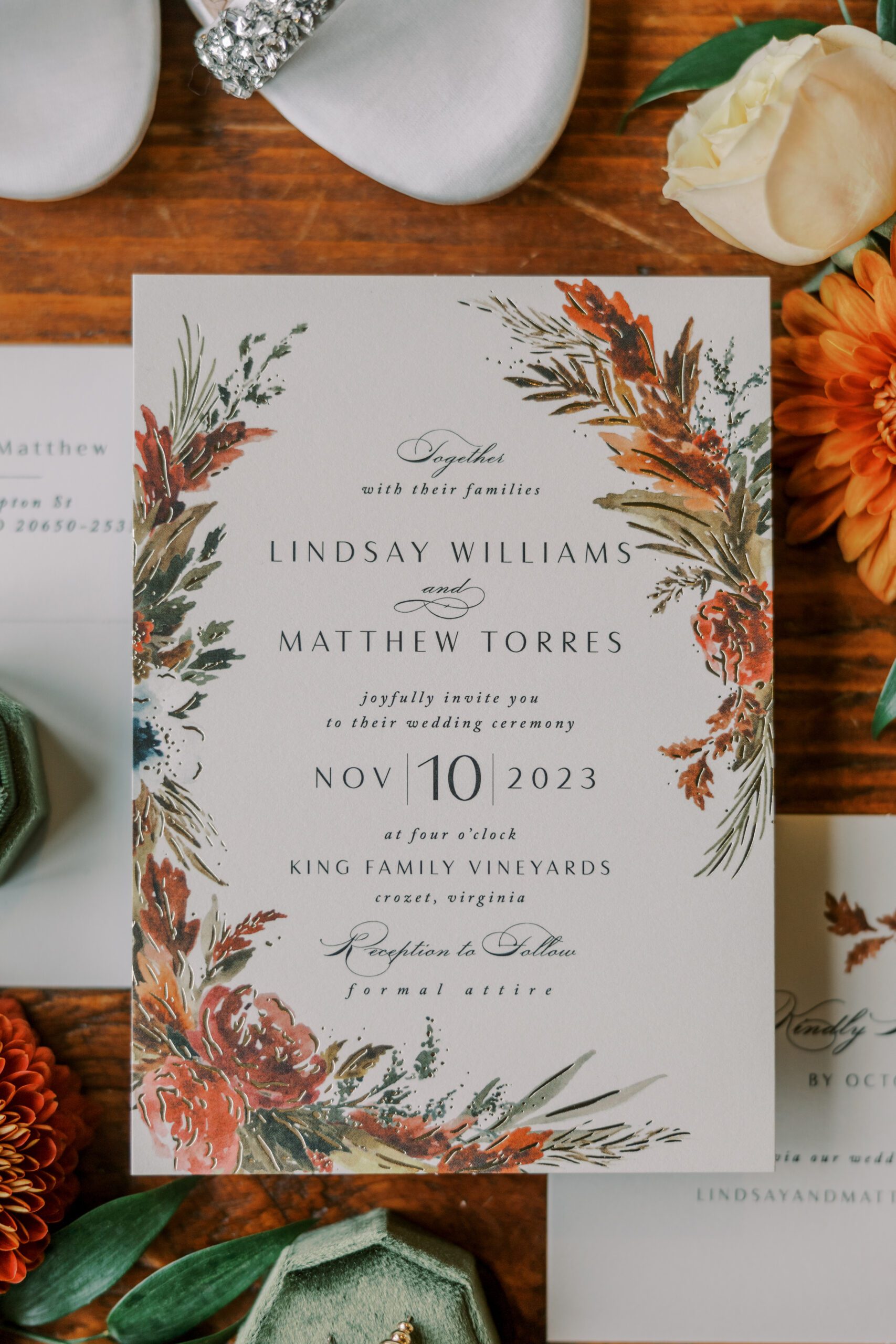Detailed photo of white wedding invitation with orange, burgundy and green floral print on sides