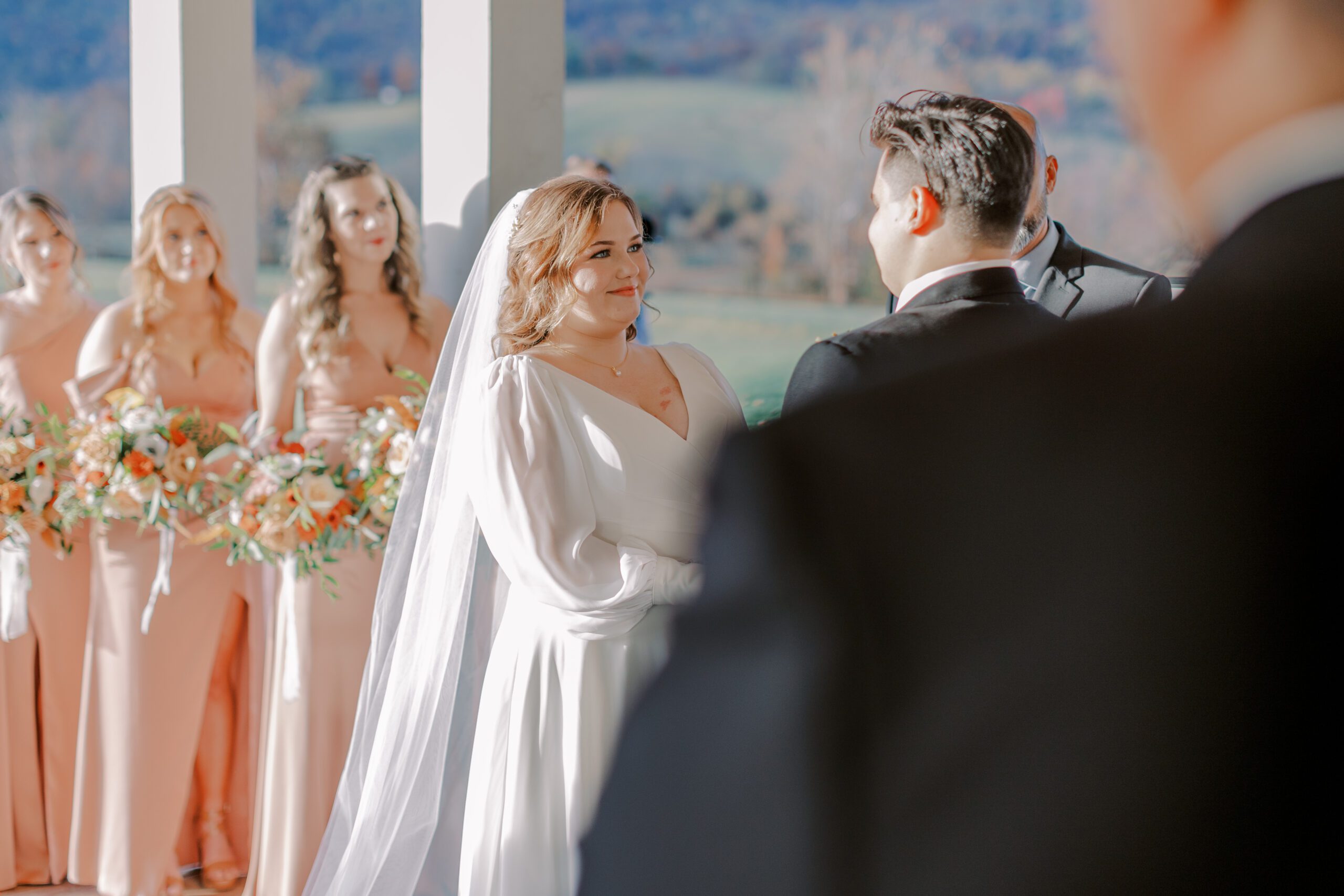 Image of bride smiling at groom, bridesmaids in background holding their flowers