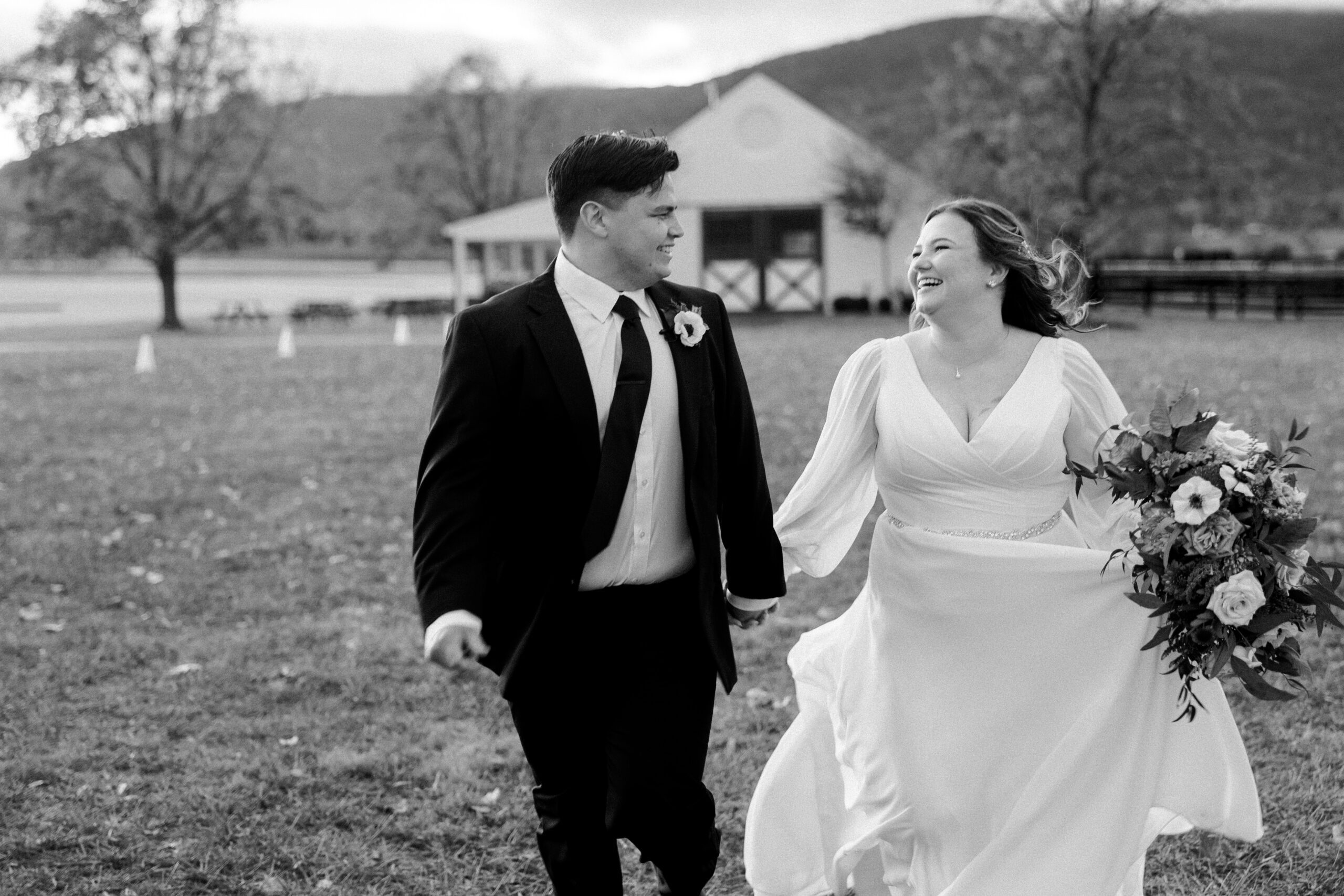 Black and white photo og bride and groom running and laughing together ar king family vineyards