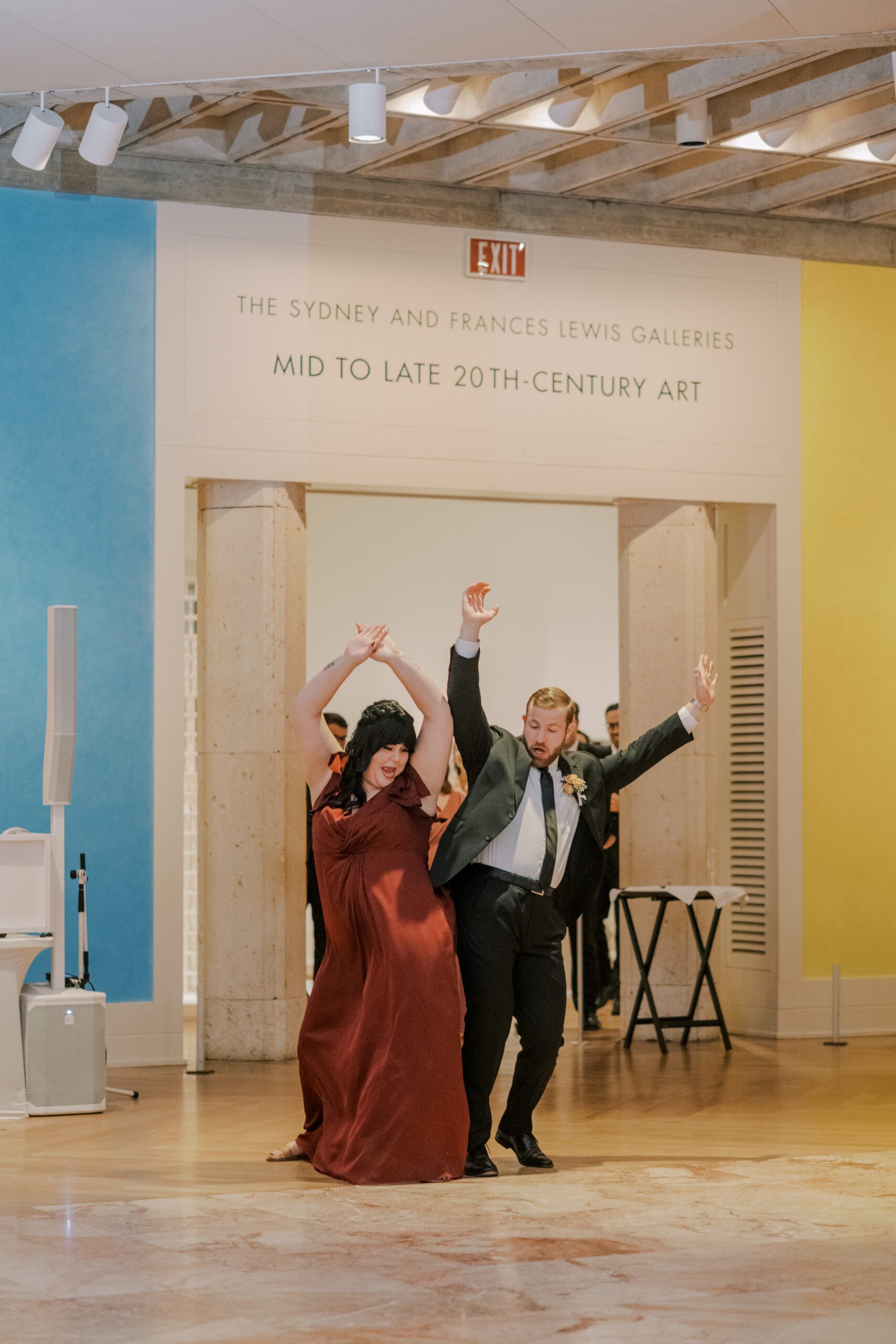 Bridesmaid and groomsmen enter reception with their arms up, bumping hips with one another at vmfa