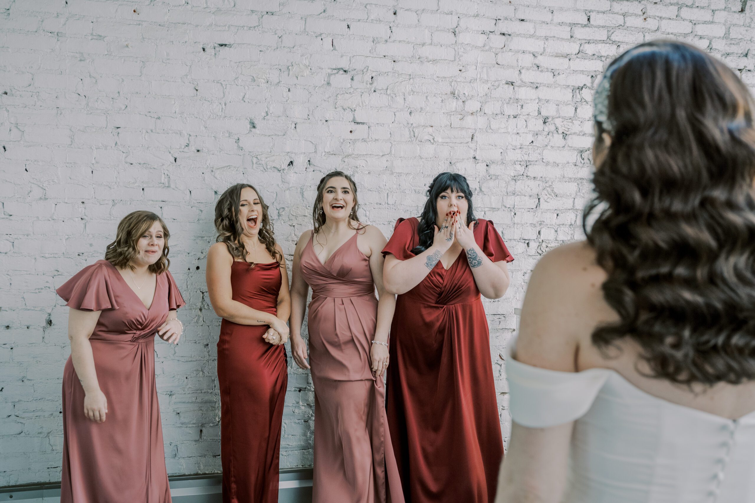 Photo of bridesmaids with surprised and excited expressions as they see bride in her dress for the first time before her vmfa fall wedding
