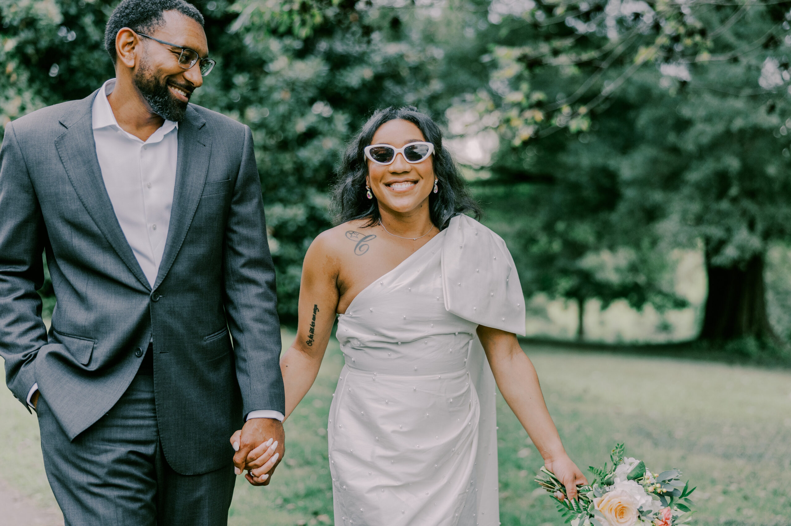 Woman smiling at camera wearing white sunglasses, as man looks over at her smiling at their maymont september engagement session