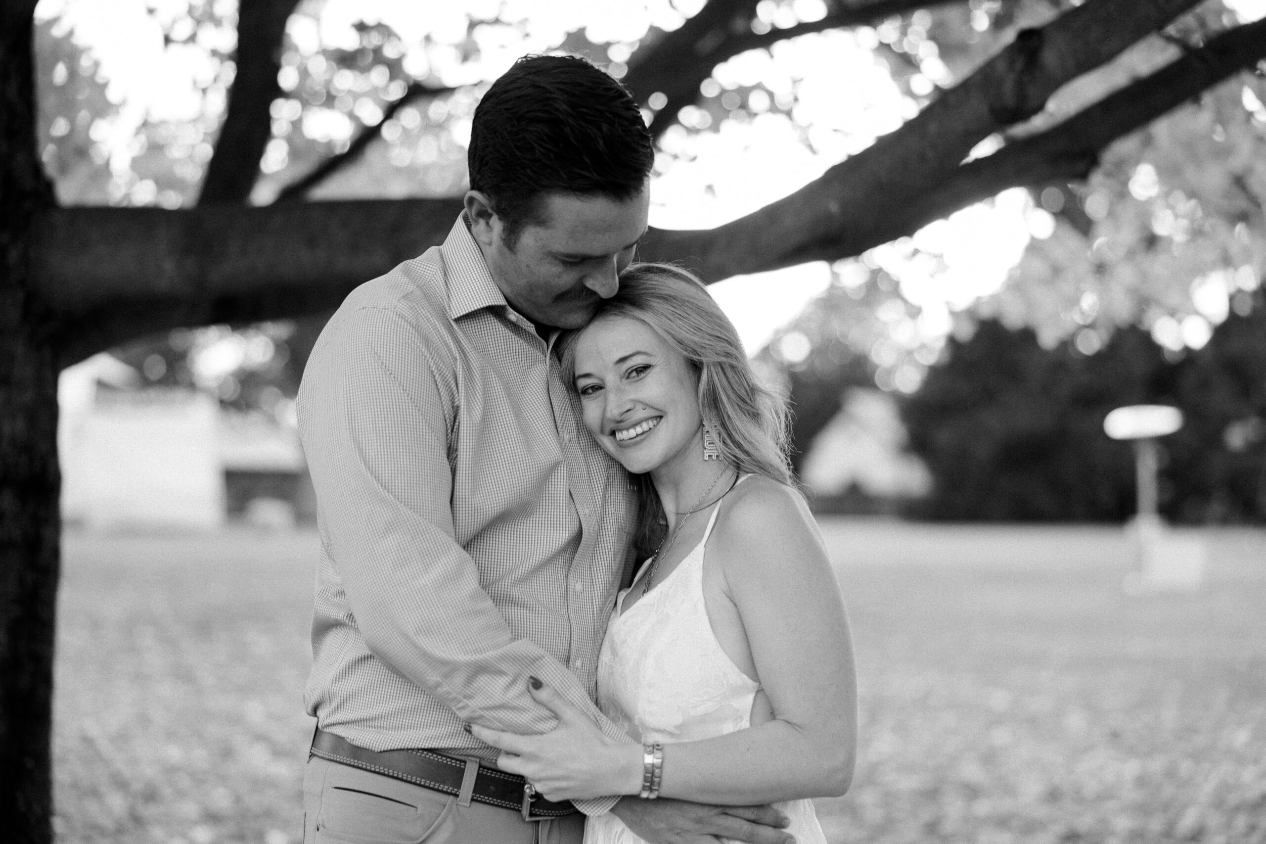 black and white image of man hugging woman while she smiles at camera at maymont