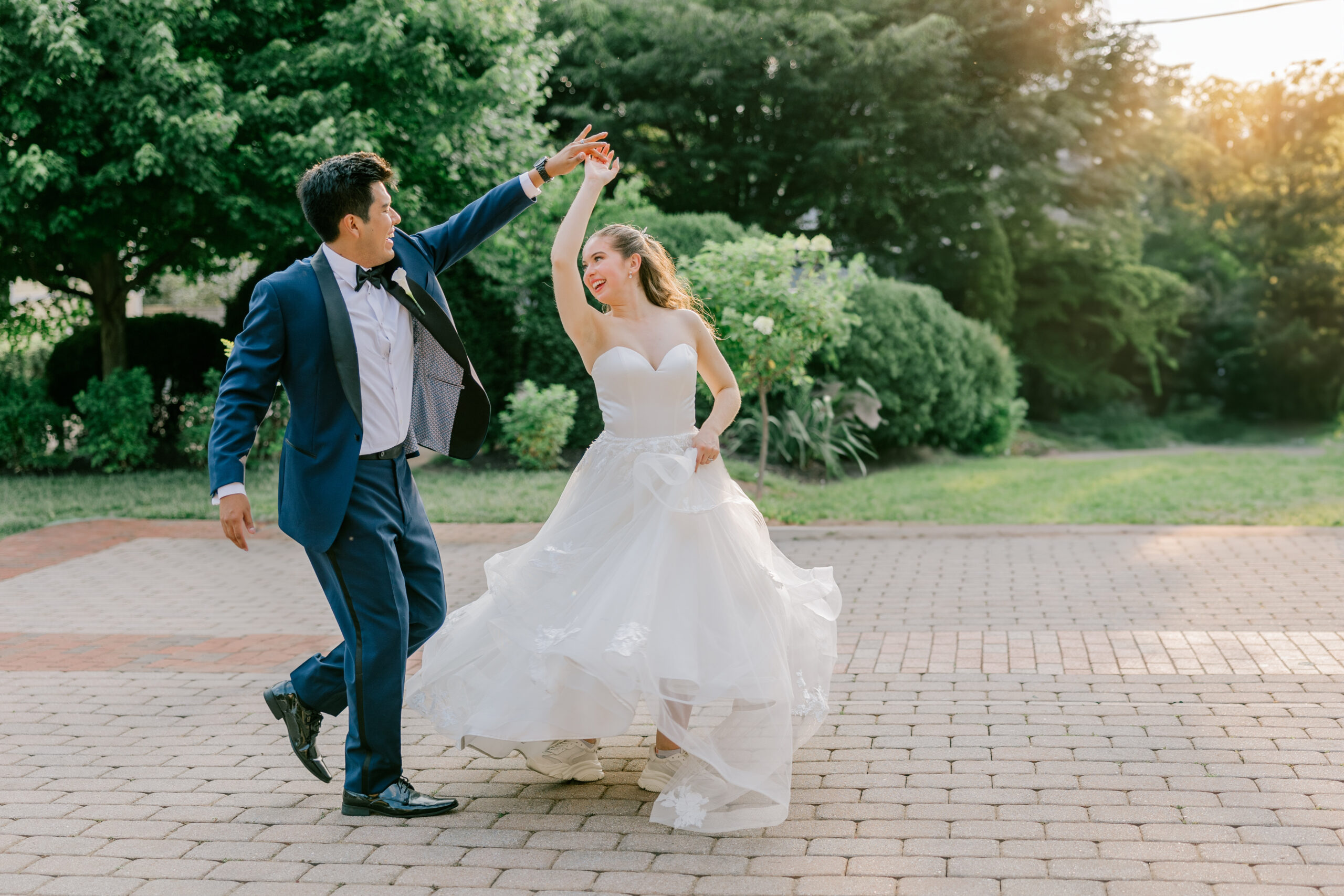 the bride and groom twirl during their posed portraits on their wedding day at Birkby House