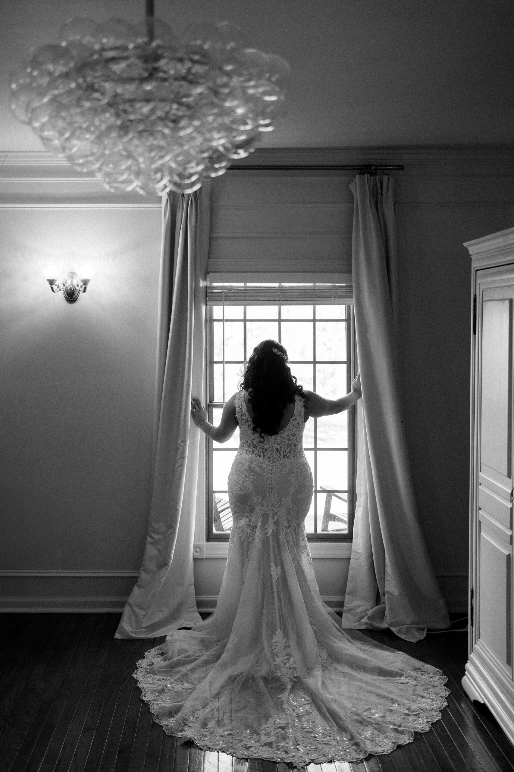 the bride looks out the window of the venue's bridal suite