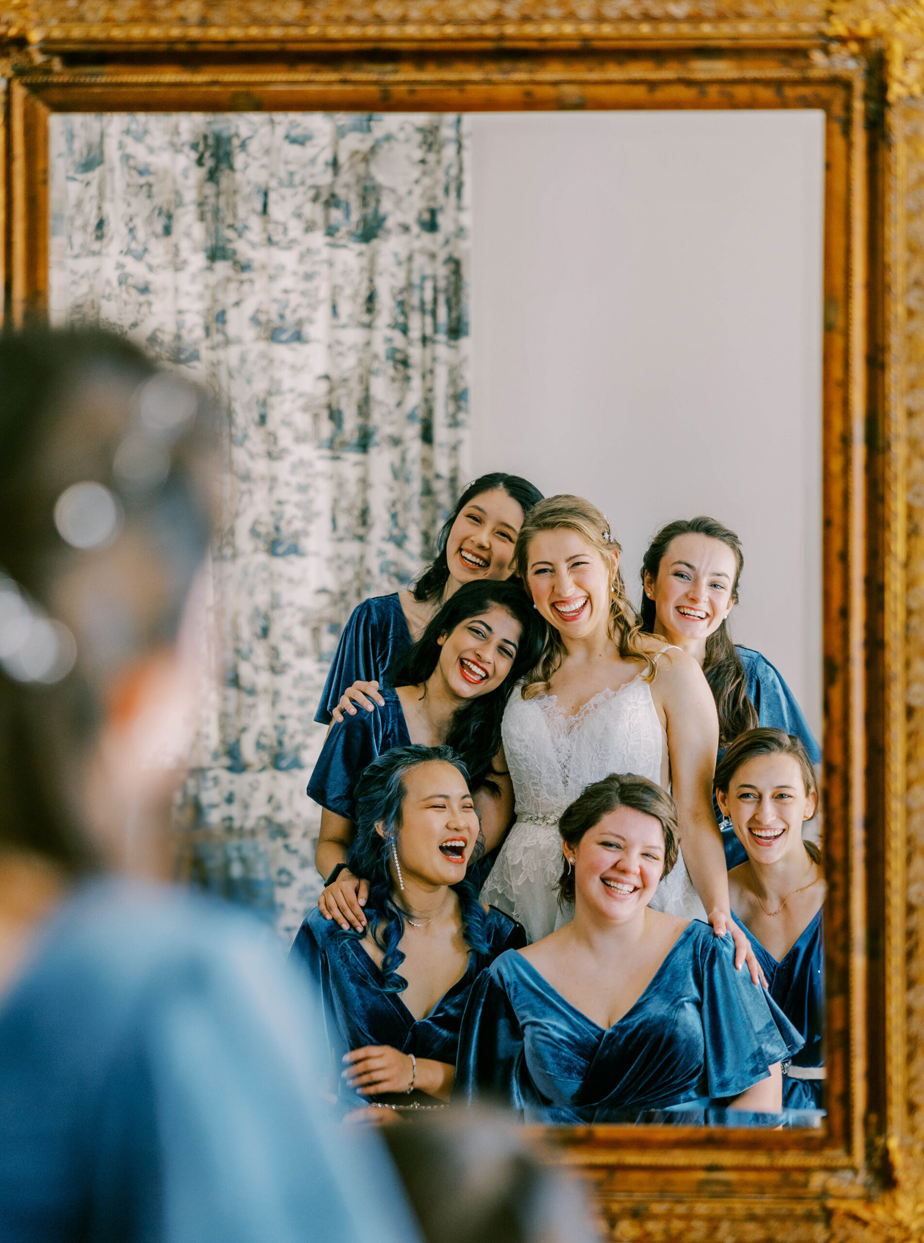 bridesmaids pose for a photo in a mirror framed on the wall of the bridal suite