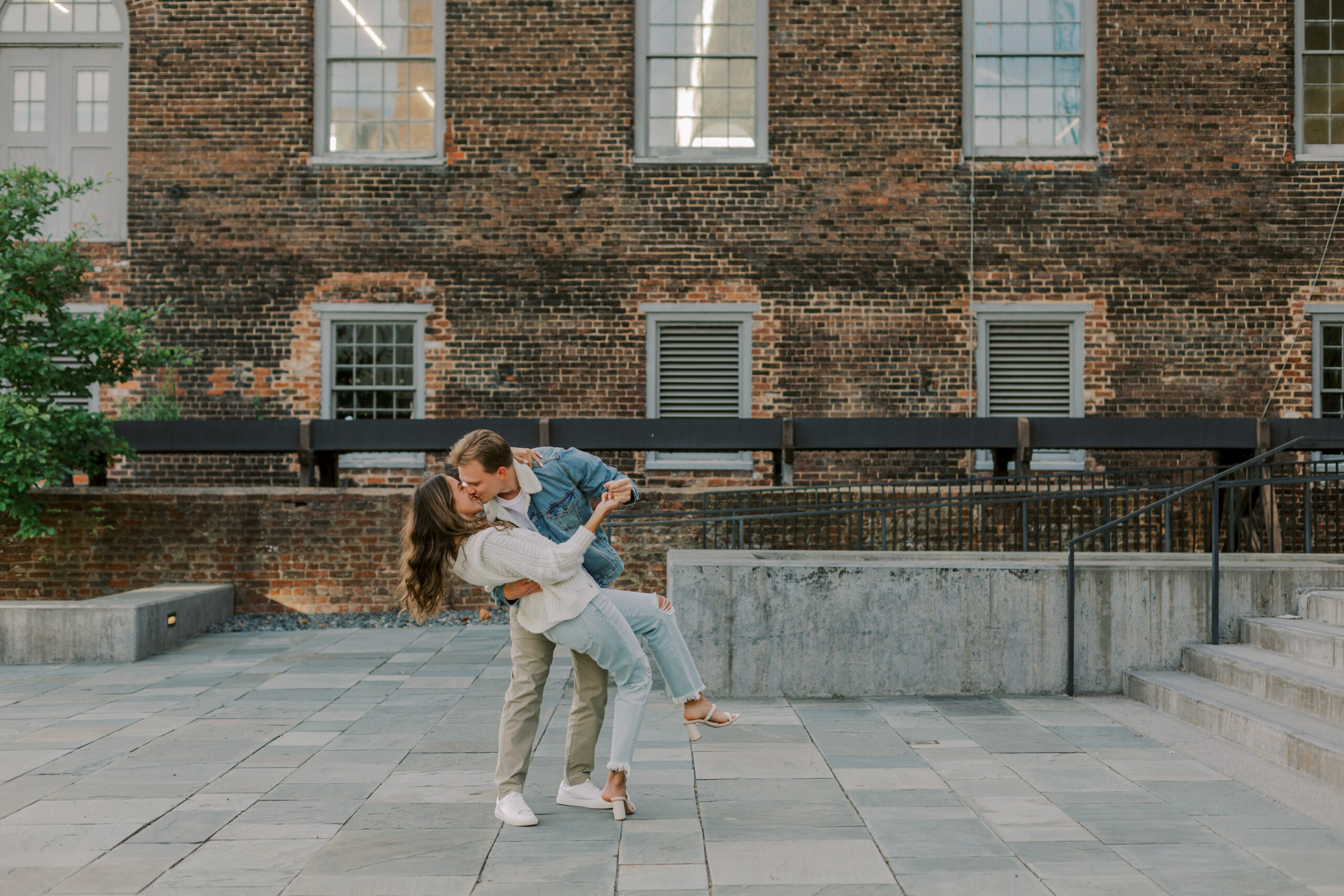 Couple dancing and kissing, with the brick tredegar ironworks building in the background
