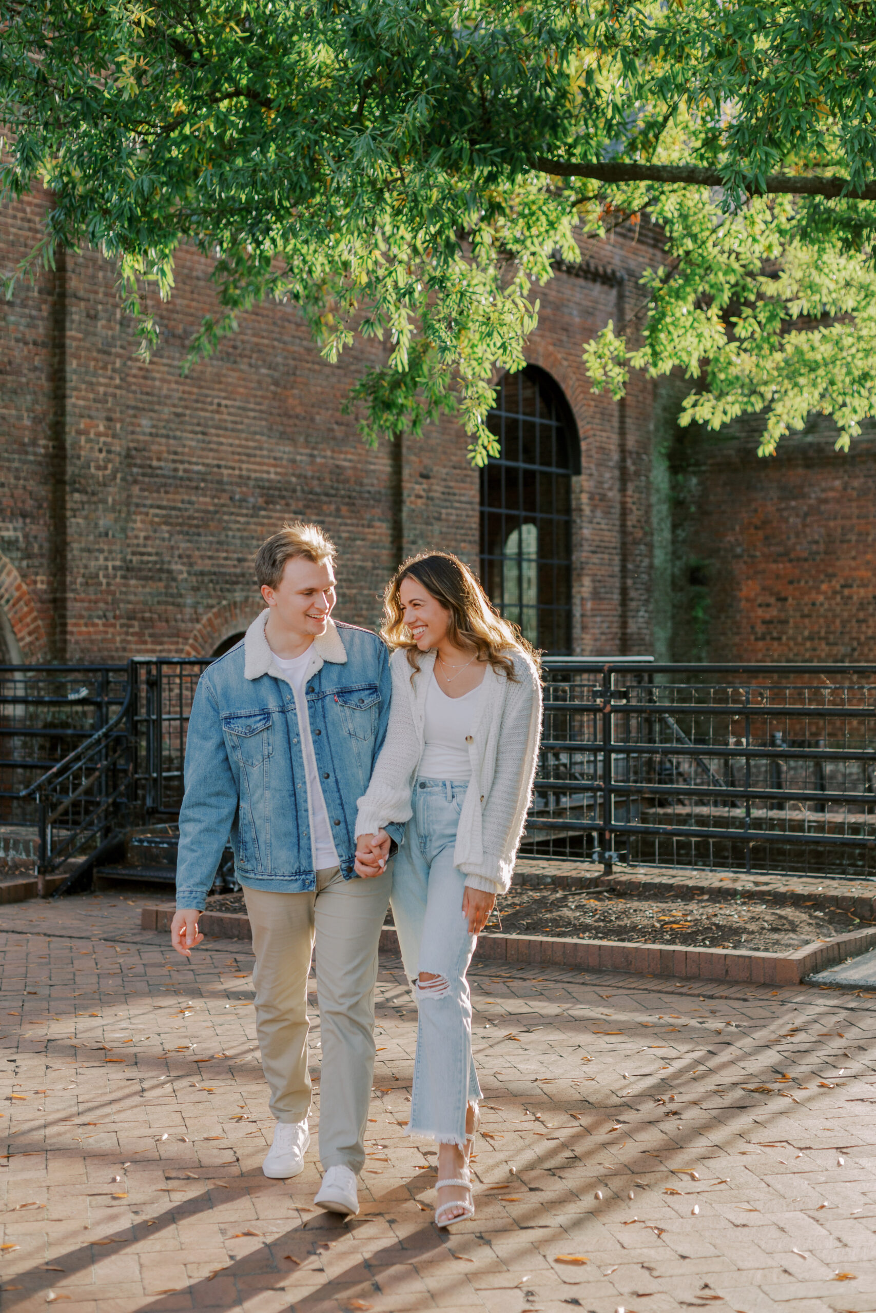 Man and woman holding hands, walking and laughing at their tredegar ironworks fall engagement session