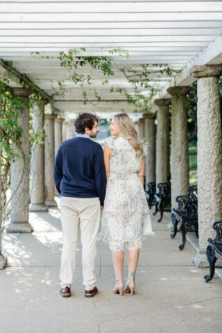 Man and woman walking holding hands walking under the pergola at maymont park