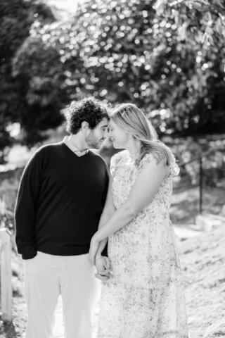 Black and white photo of engaged couple holding hands and touching noses