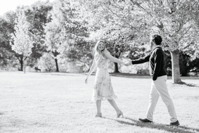 Man and woman walking hand in hand, woman leading the man as she looks back and smiles at him