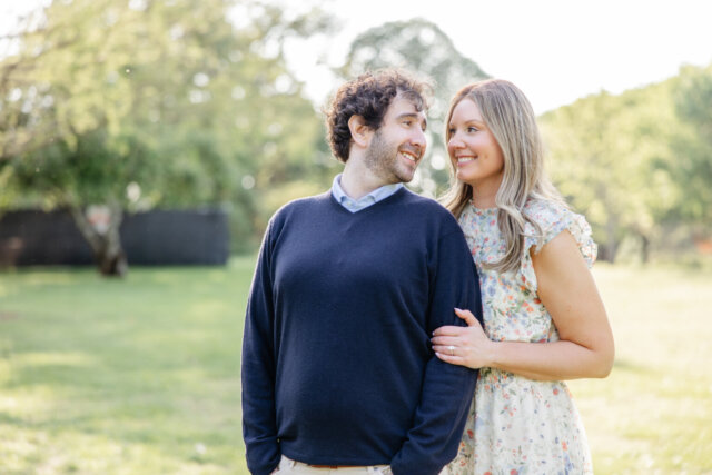 Woman standing behind man holding his arm as he smiles at her back over his shoulder