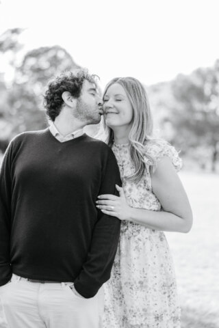 Man kissing his fiancee's cheek over his shoulder