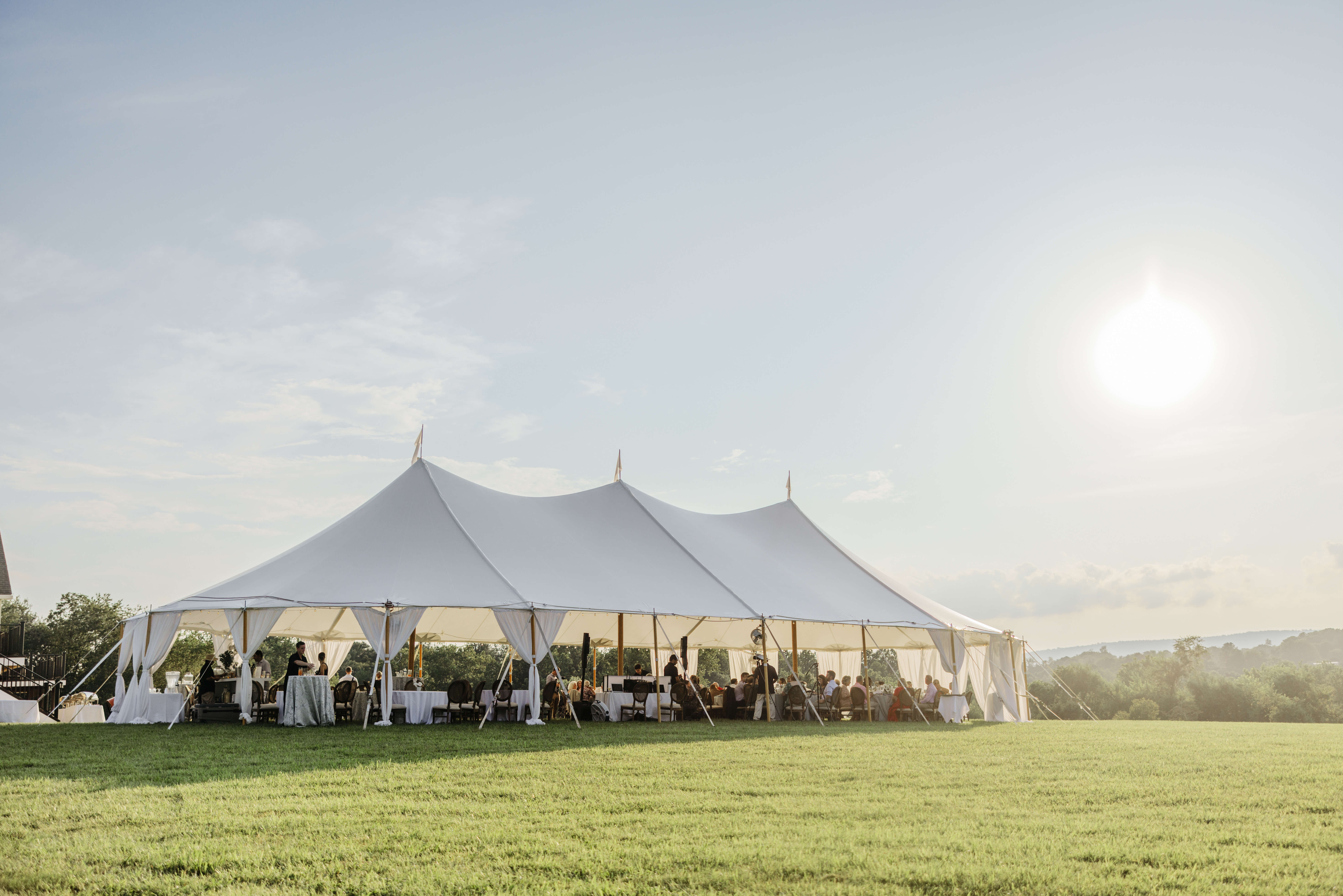 Private Residence Summer Wedding 28 Photo of the property, with the entire large white tent in view, guests sitting at tables underneath it