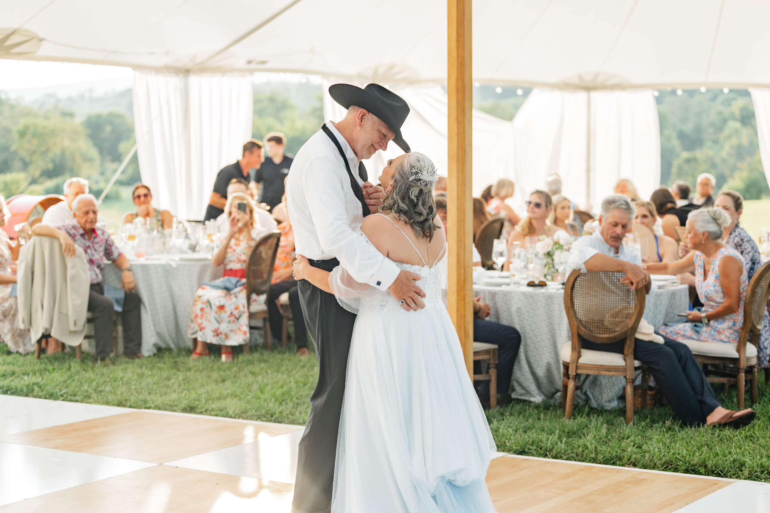 Private Residence Summer Wedding 32 Bride and groom dancing as guests sit at tables in background watching and taking photos