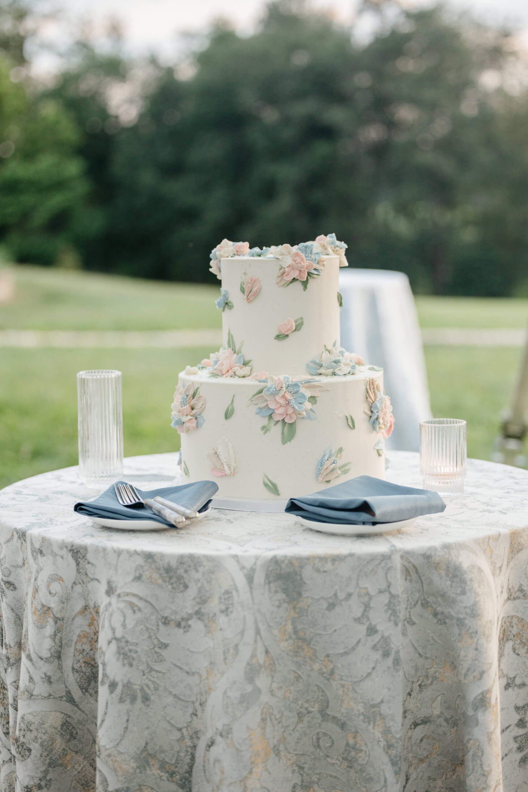 Private Residence Summer Wedding 38 Two tier white wedding cake with pink and blue iced florals on it