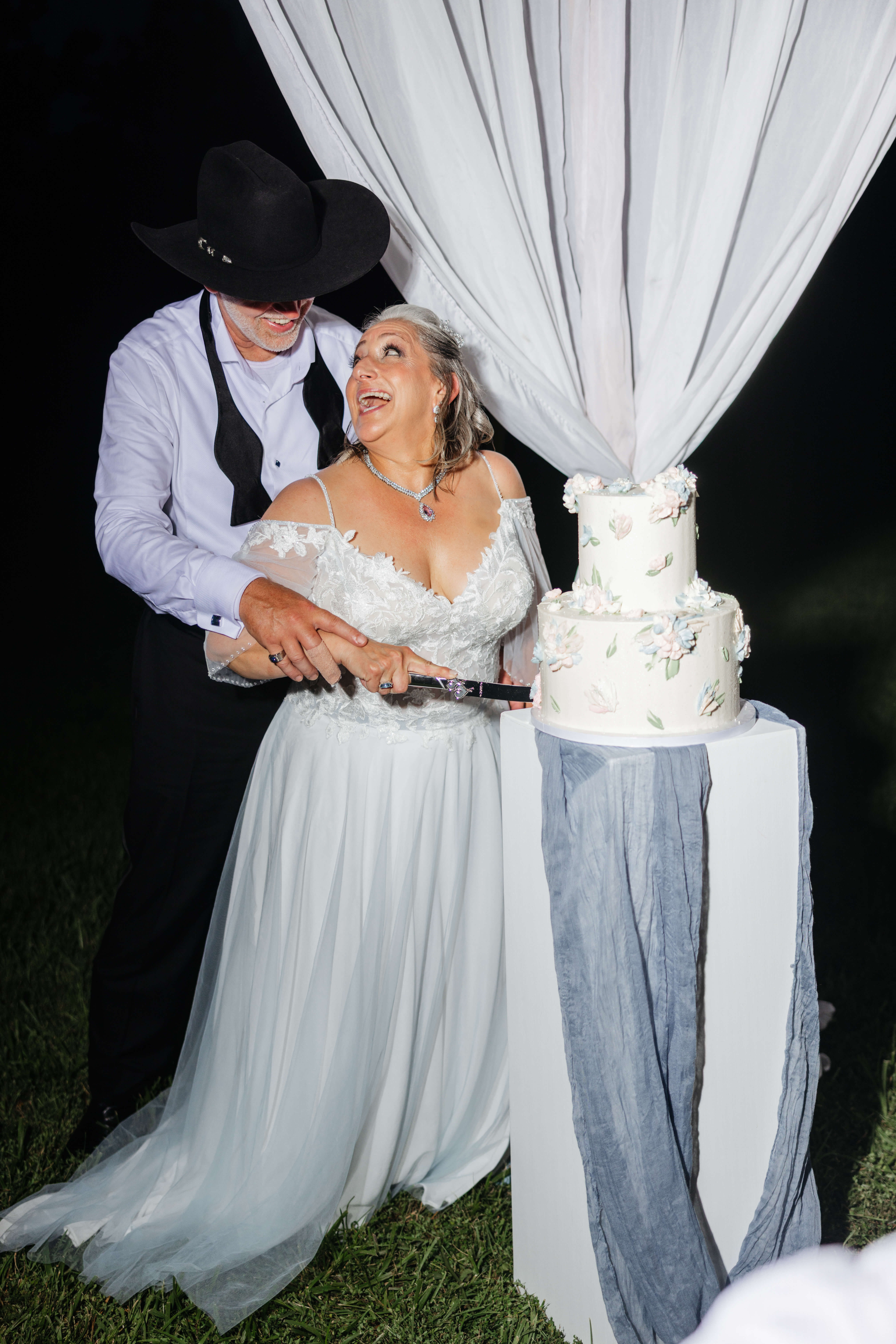 Private Residence Summer Wedding 42 Bride smiling back up at groom as they cut their wedding cake
