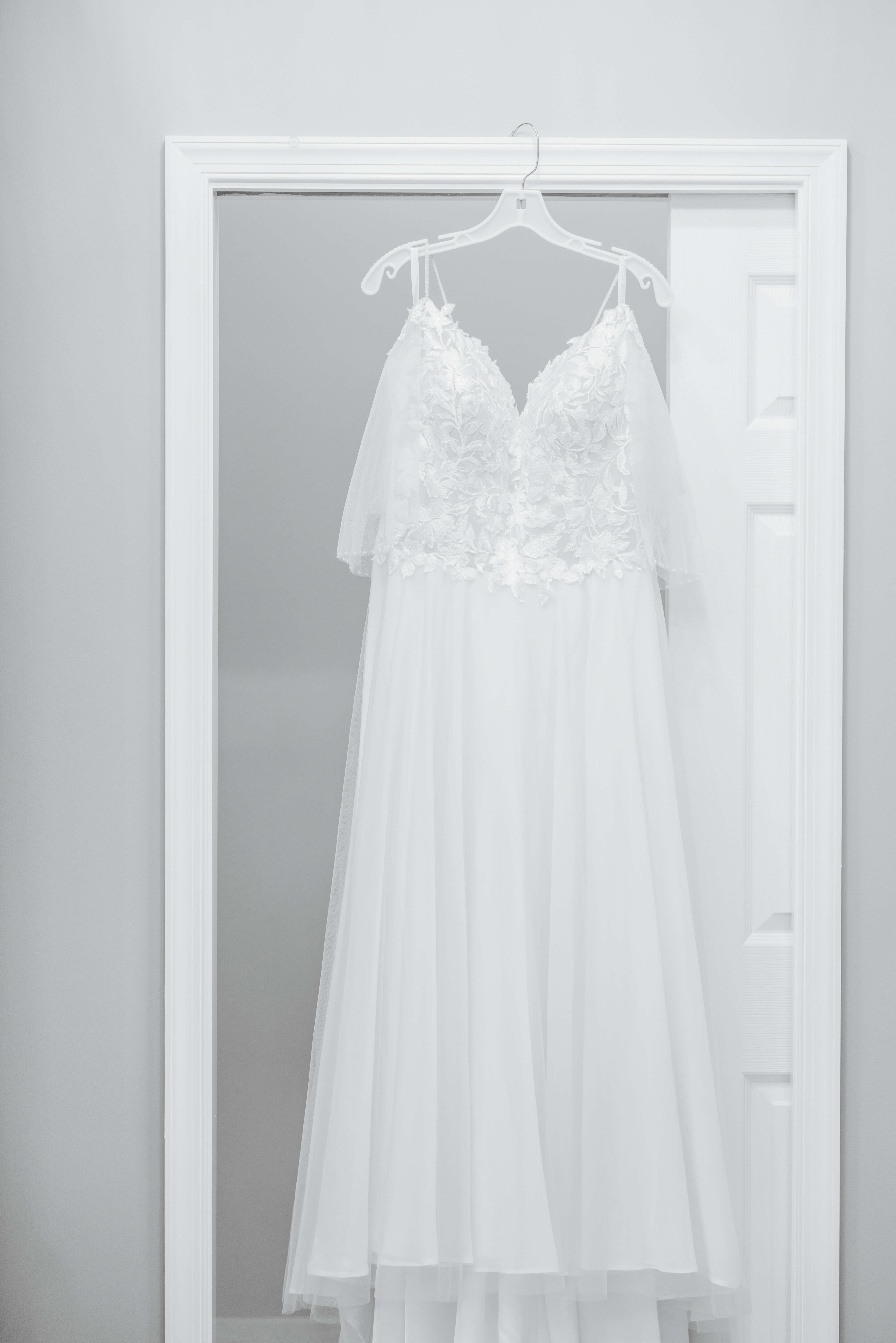 Private Residence Summer Wedding 2 Black and white photo of bride's dress hanging on door frame