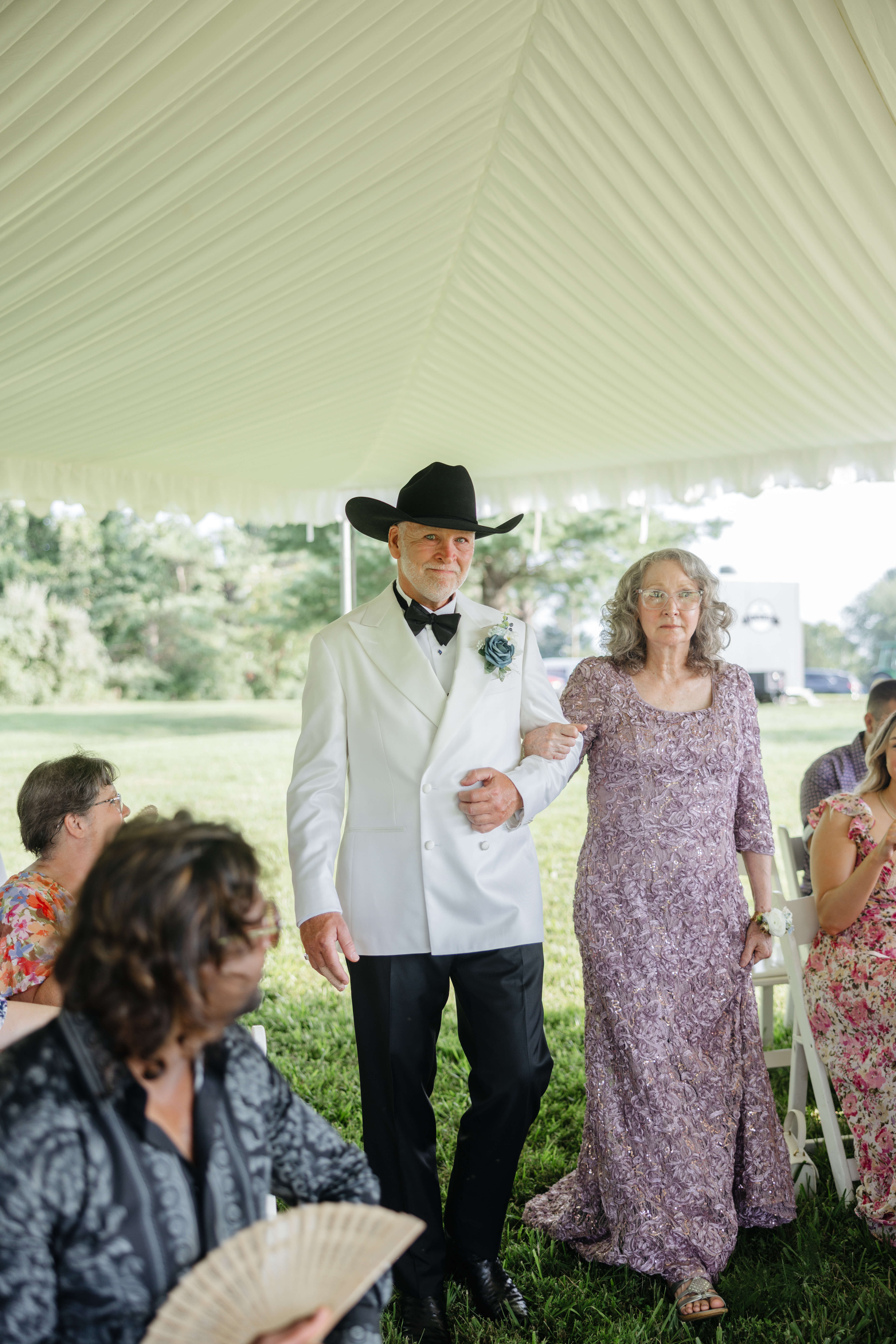 Private Residence Summer Wedding 11 Groom walking down aisle with a slightly emotional expression on his face walking arm in arm with a woman in a purple dress