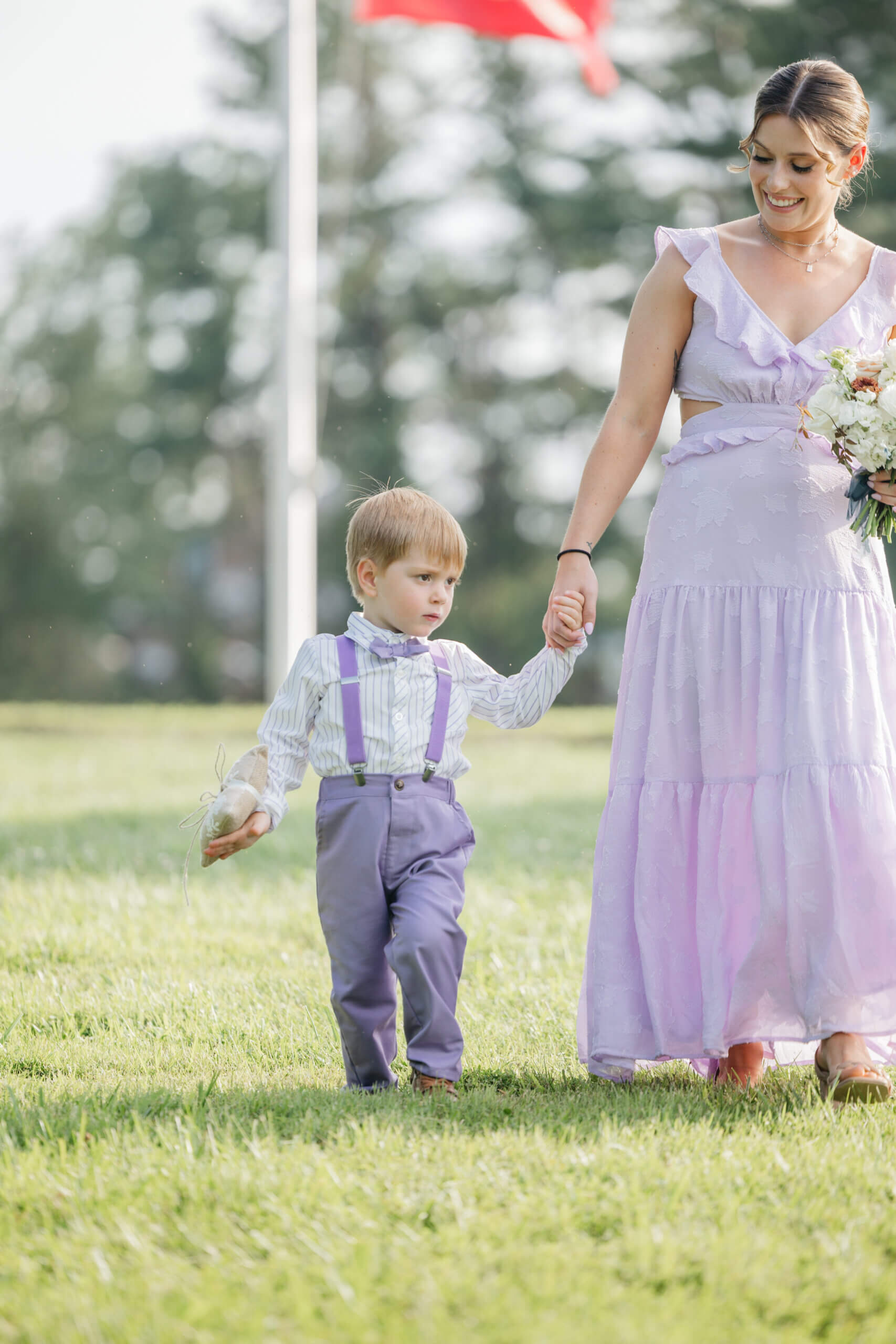 Private Residence Summer Wedding 12 Woman in light purple dress walks with little boy in purple suit