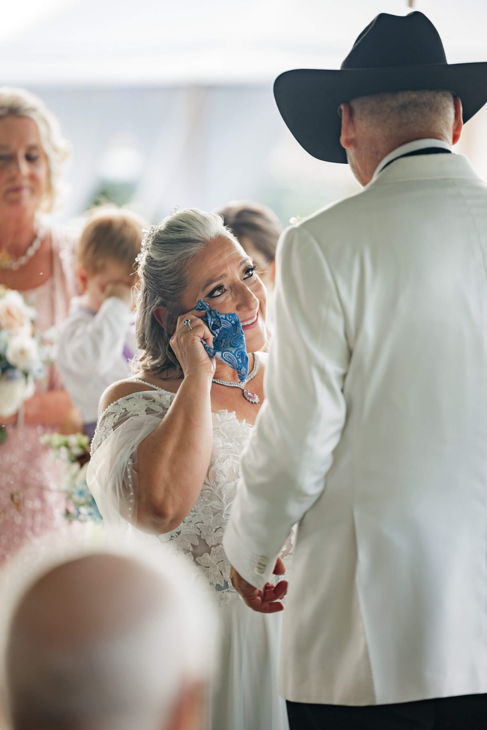 Private Residence Summer Wedding 17 Bride wiping a tear from her eye as she looks up at groom smiling