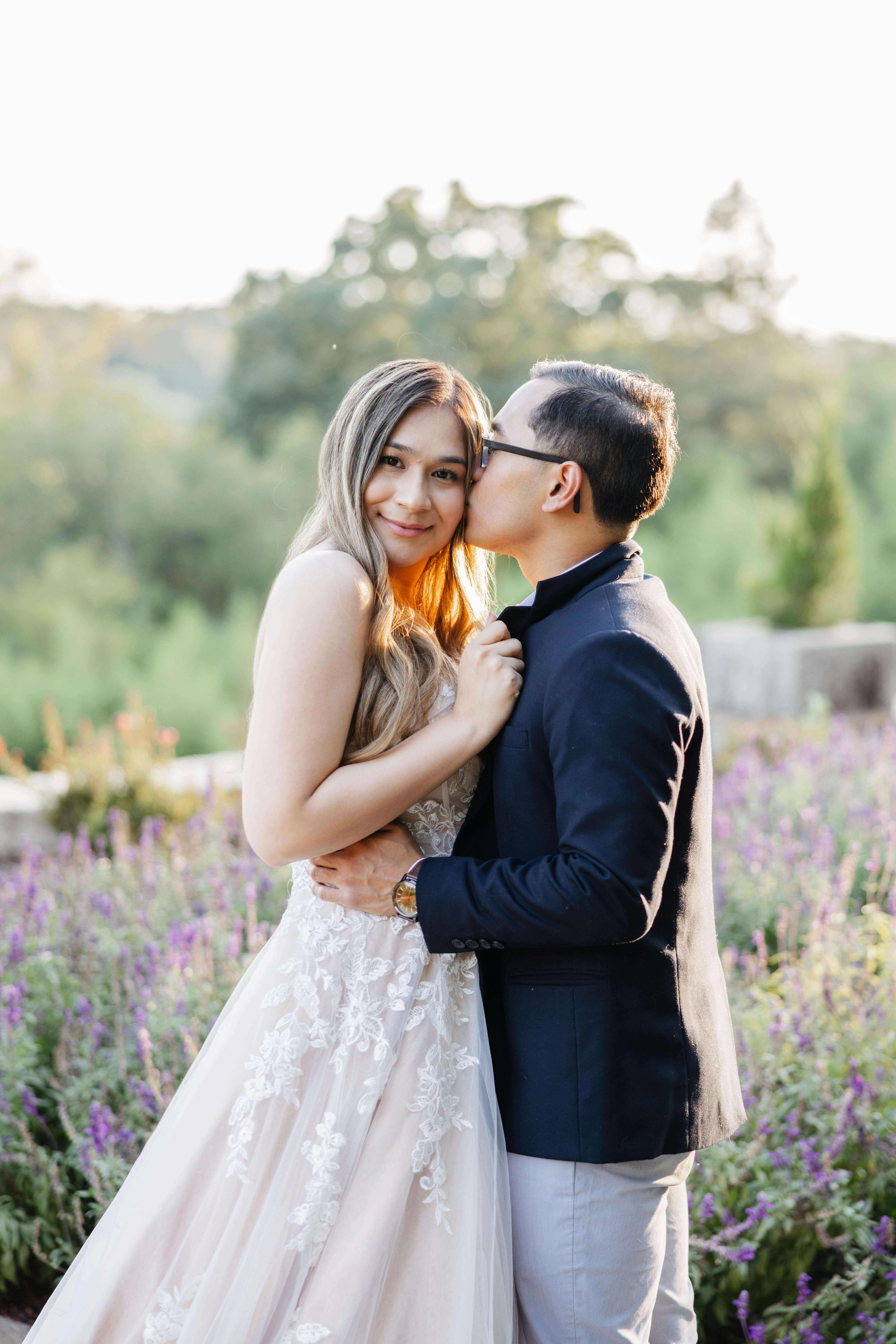 Maymont Park Engagement Summer Photography 13 Man kissind woman's head as she smiles at camera and holds onto man's suit jacket