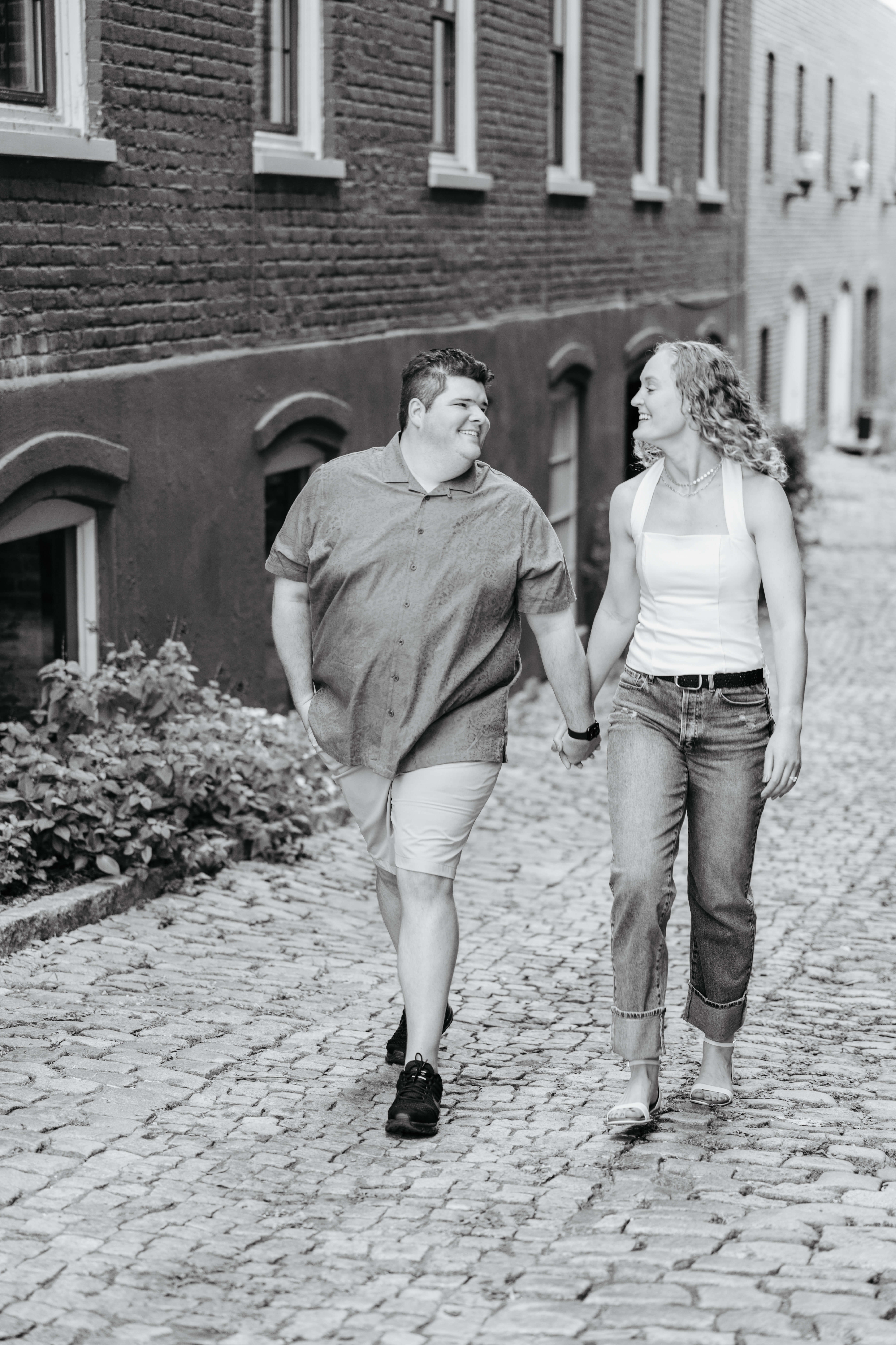 Shockhoe Bottom Fall Engagement Photography 3 Black and white photo of engaged man and woman walking hand in hand on stone pathway as they smile at one another