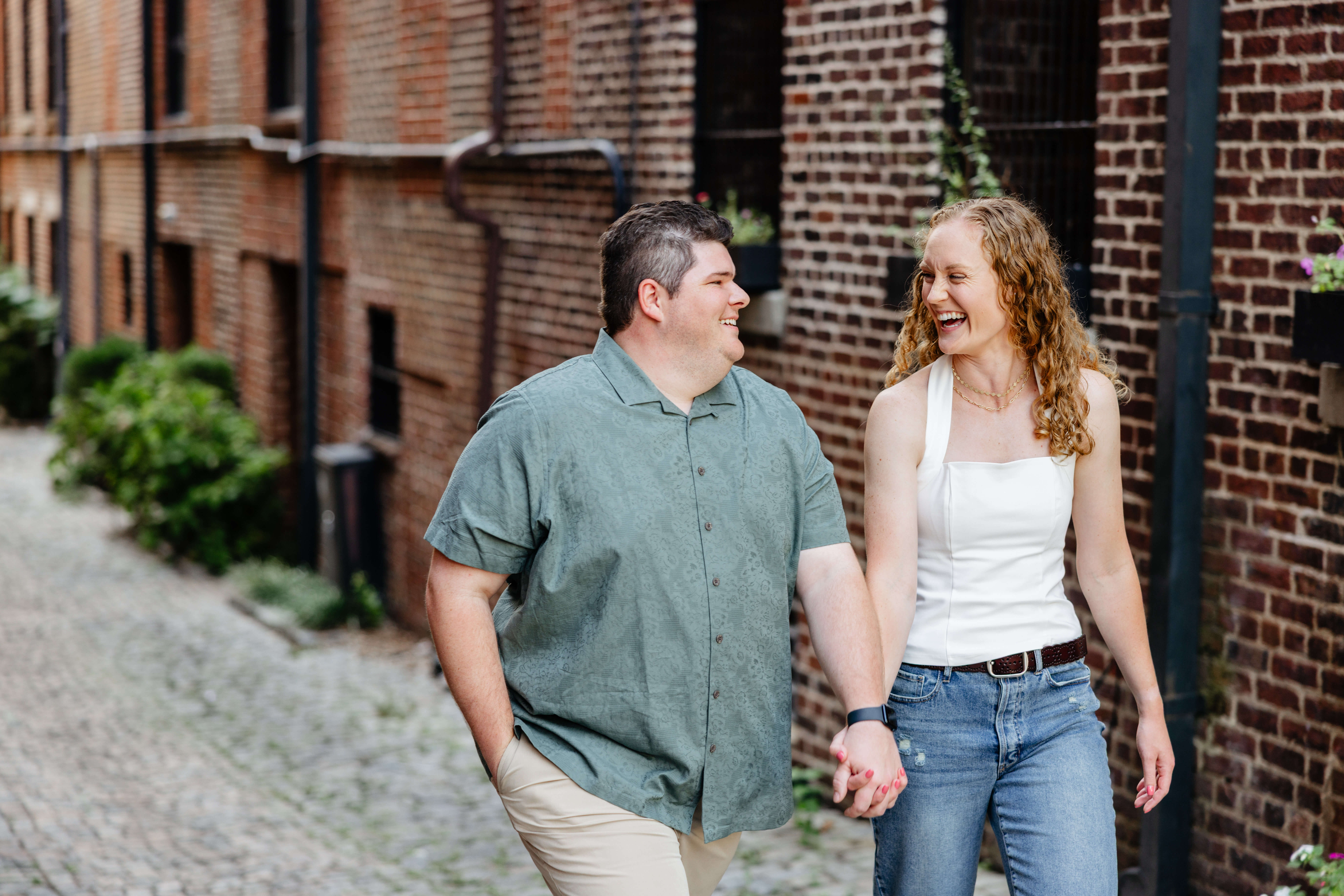 Shockhoe Bottom Fall Engagement Photography 4 Man and woman smiling and laughing with one another as they hold hands walking down a stone pathway in shockhoe bottom