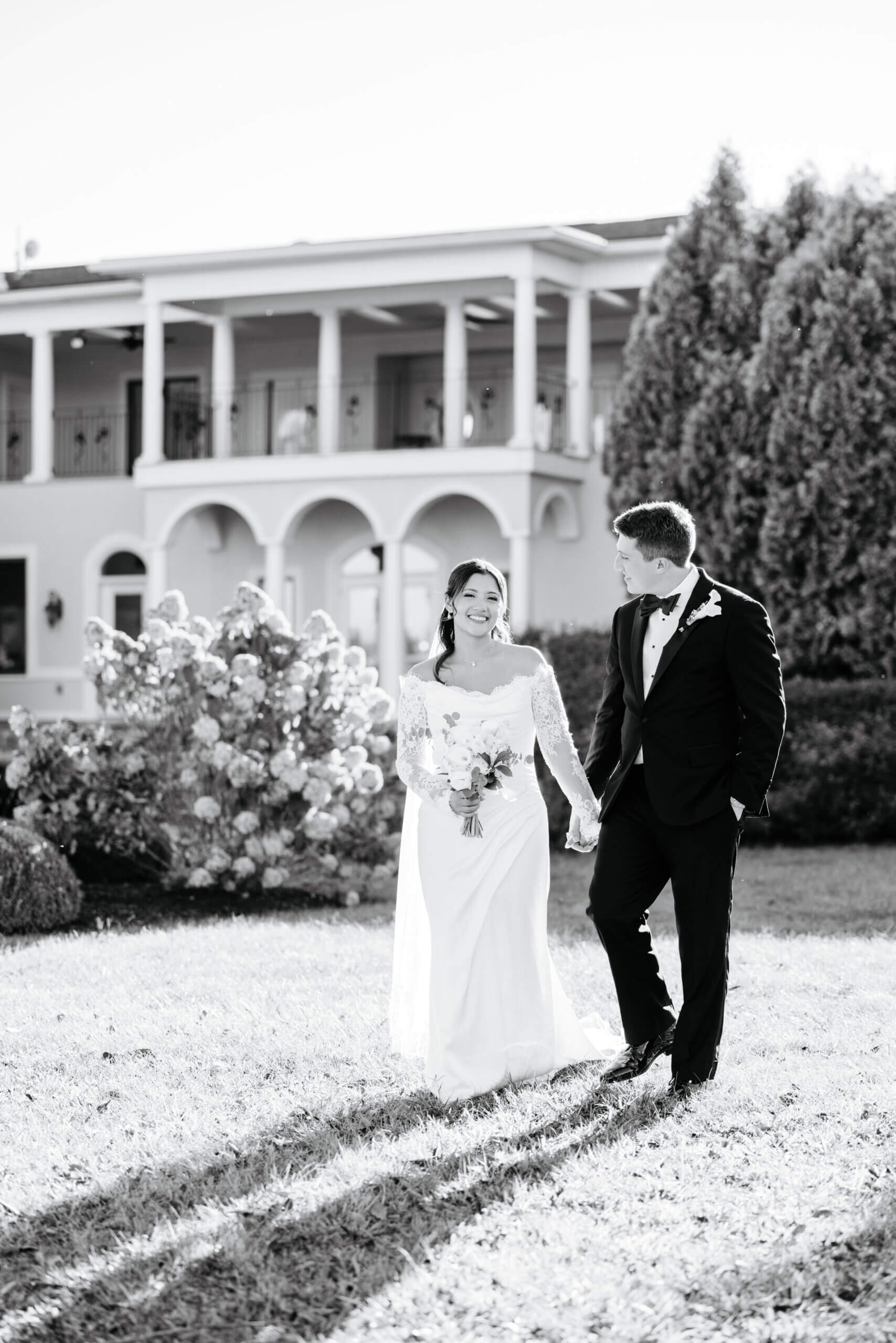 CrossKeys Vineyard Fall Wedding Photography 27 Black and white photo of bride and groom walking hand in hand with crosskeys vineyard in background