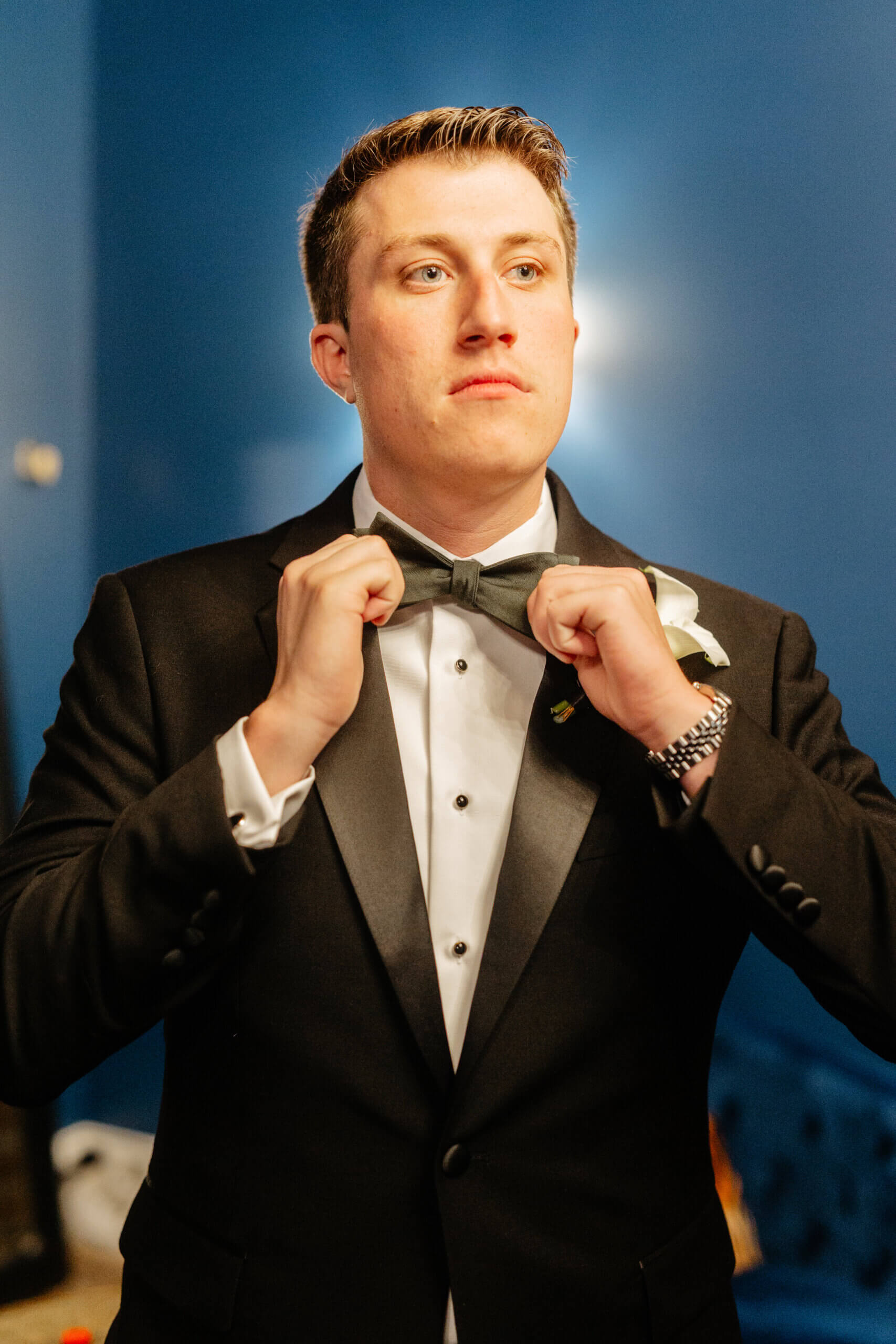 CrossKeys Vineyard Fall Wedding Photography 7 Groom with back light behind him in suit adjusts his bow tie while looking off to side
