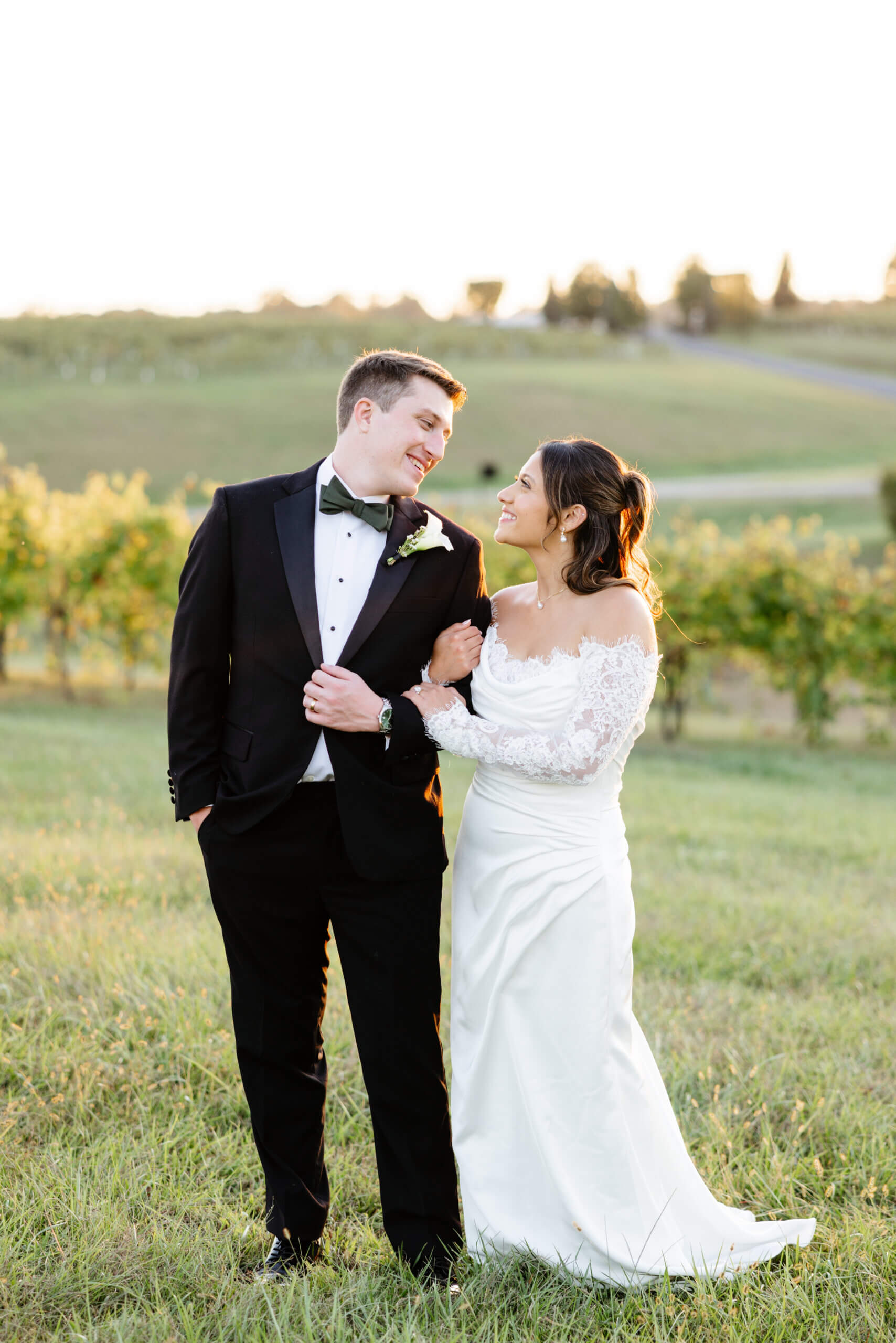CrossKeys Vineyard Fall Wedding Photography 43 Bride hugging groom's arm as he holds his suit jacket both smiling at one another outside