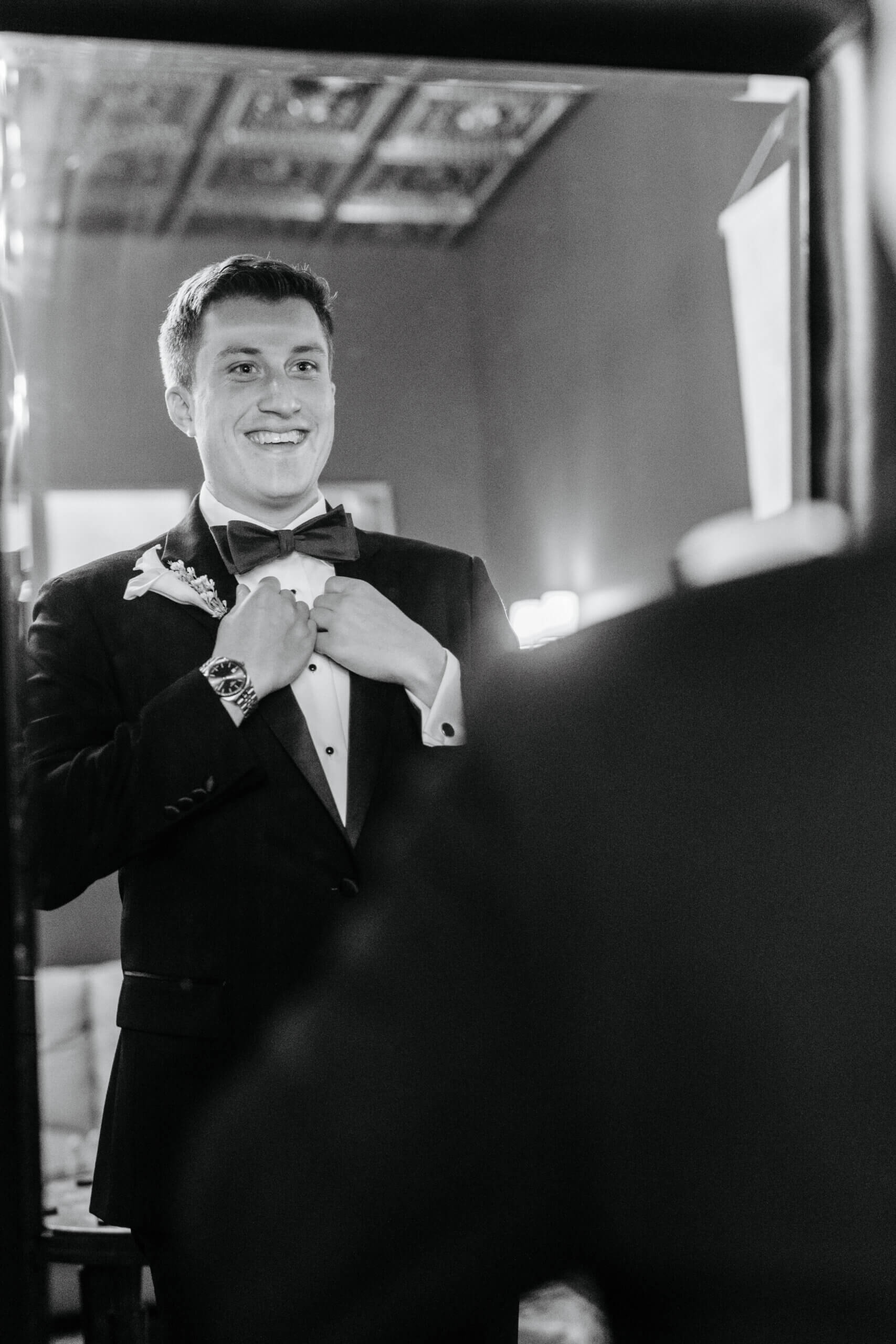 CrossKeys Vineyard Fall Wedding Photography 8 Groom looking at his reflection in mirror smiling as he holds onto his jacket