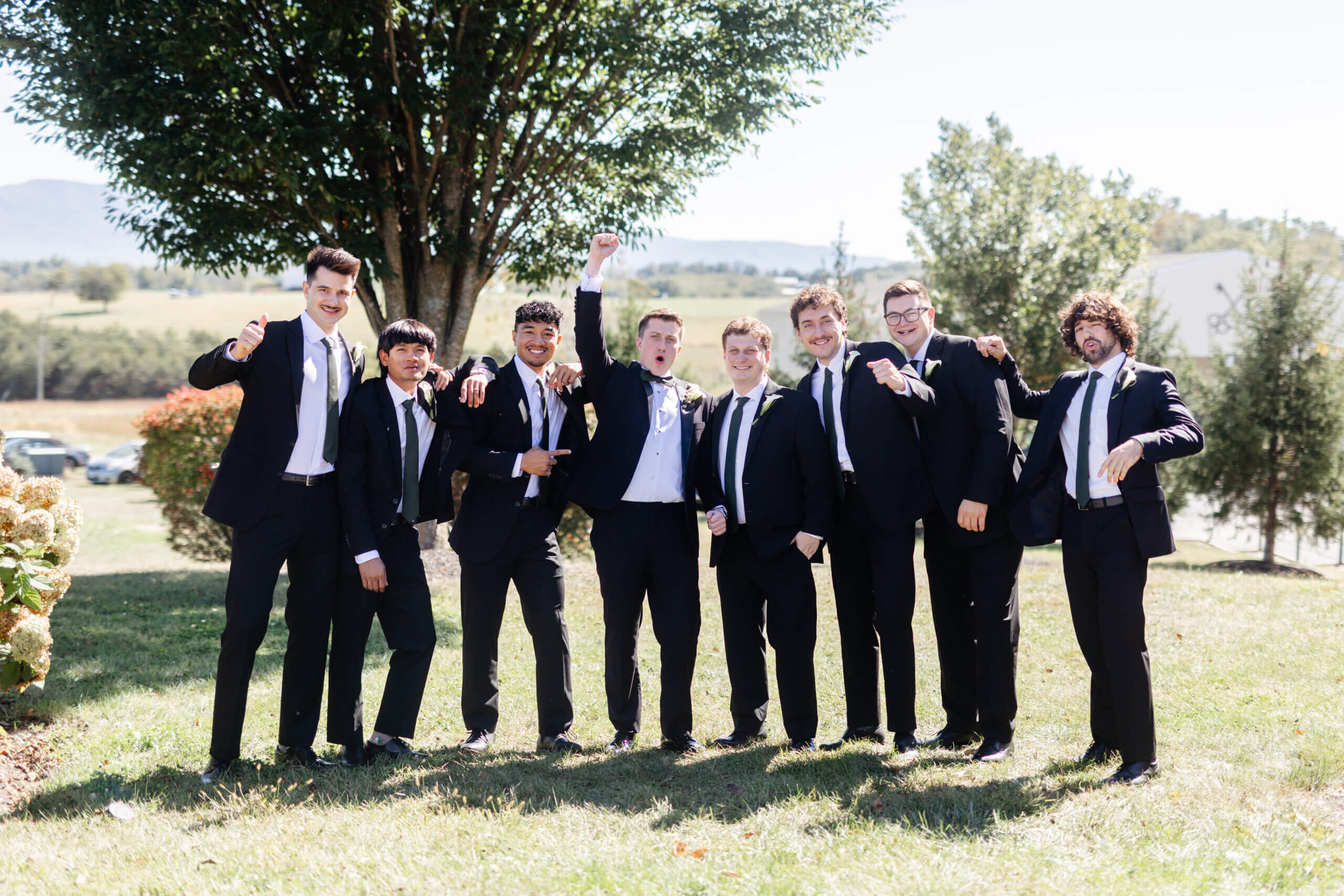 CrossKeys Vineyard Fall Wedding Photography 9 Groom and his seven groomsmen stand outside in matching black suits at crosskeys vineyard all smiling, cheering