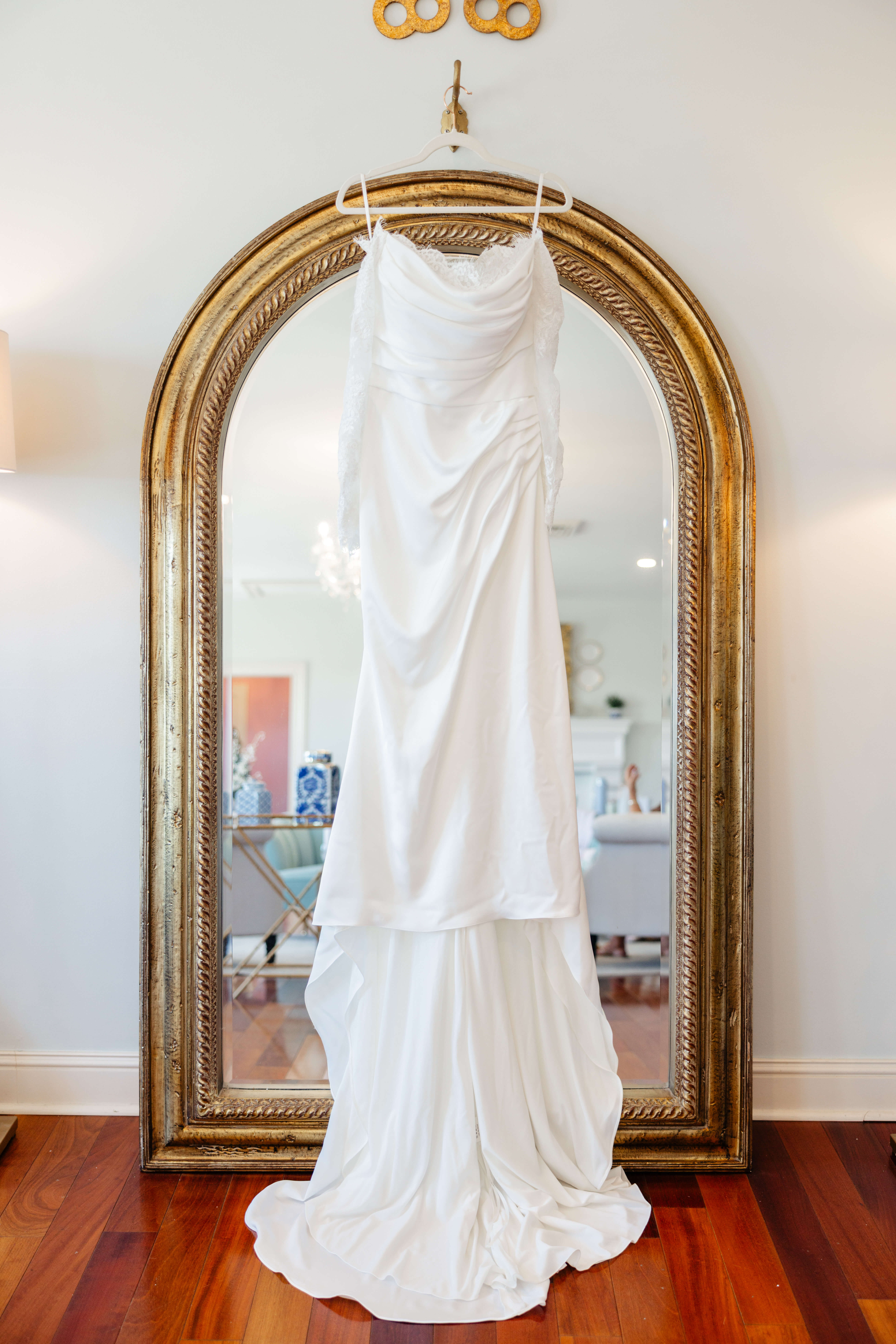 CrossKeys Vineyard Fall Wedding Photography 2 Bride's white wedding dress hangs on hook above large gold arched mirror