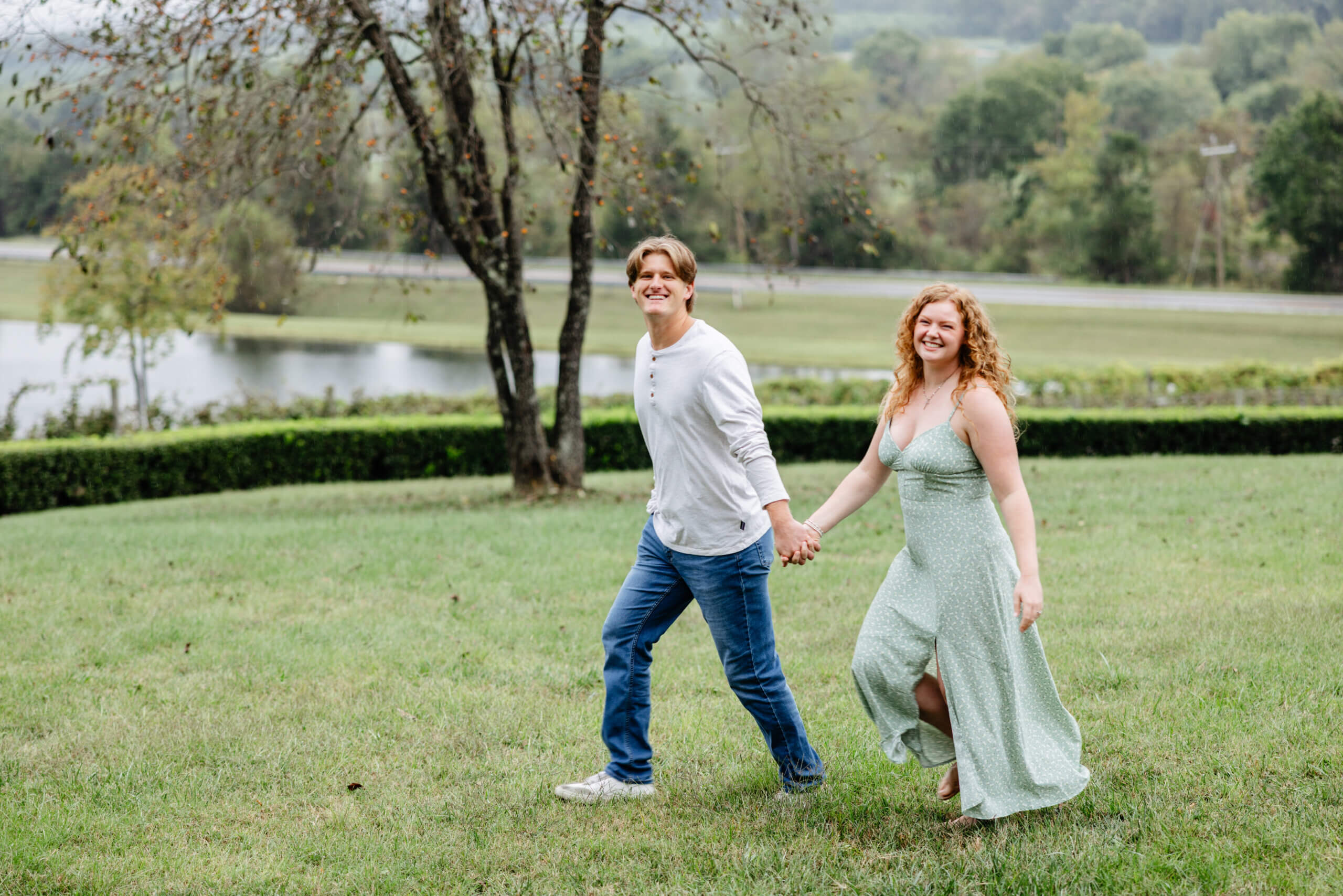 Rassawek Vineyards Fall Engagement Photography 2 Man walking hand in hand with his fiancee who is walking slightly behind him both smiling at camera