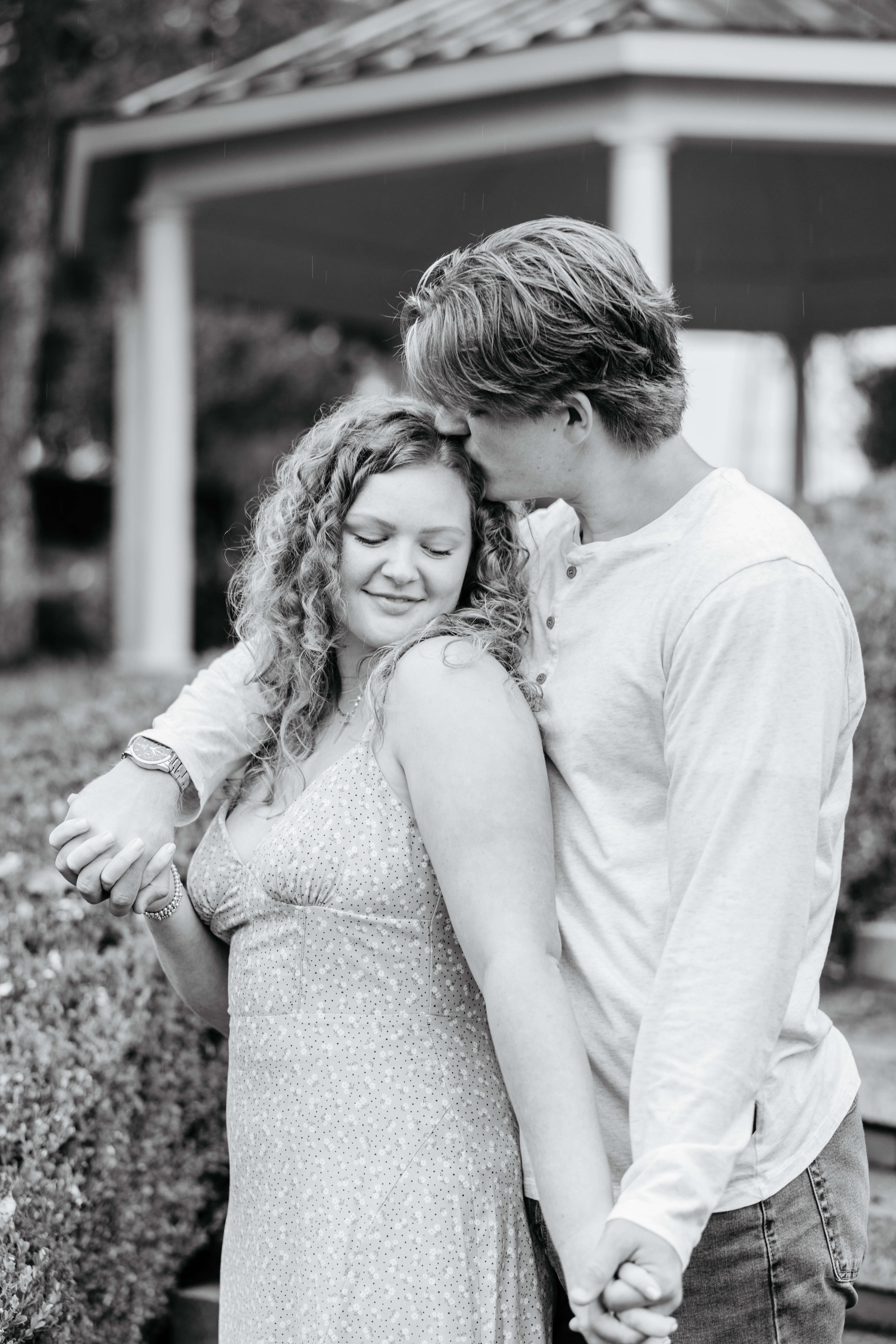 Rassawek Vineyards Fall Engagement Photography 5 Black and white photo of man standing behind his fiancee kissing the top of her head as she looks down smiling